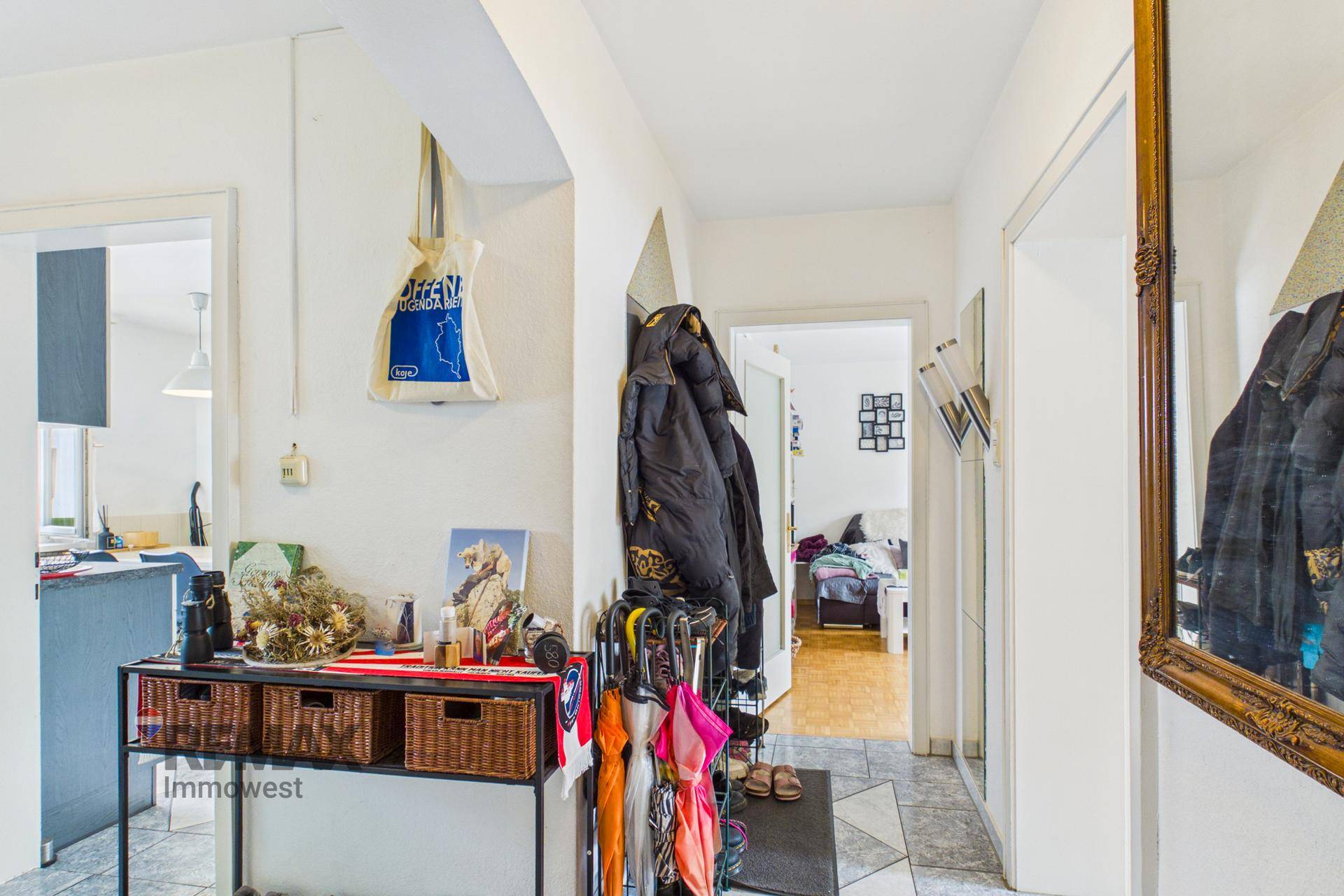Heller Eingangsbereich mit Fliesenboden, Garderobe und Spiegel.
