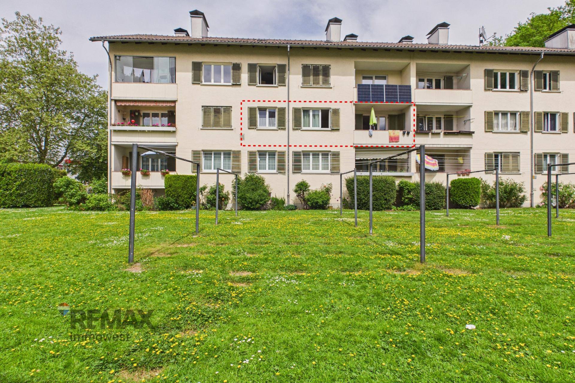 Nahaufnahme des Mehrfamilienhauses mit Balkonen und Gemeinschaftsrasenfläche.