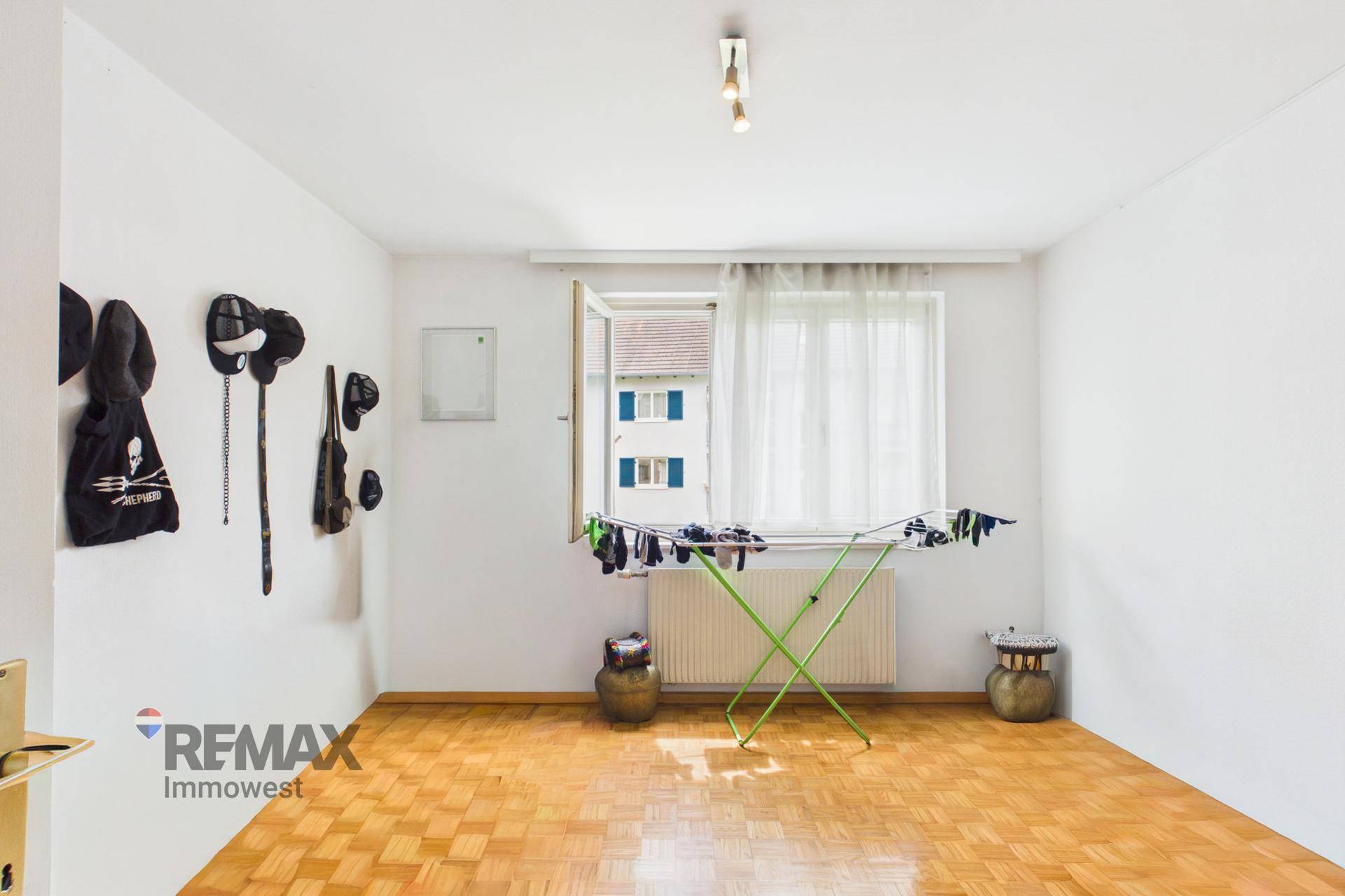 Helles Zimmer mit Parkettboden und Fenster, derzeit als Trockenraum genutzt.