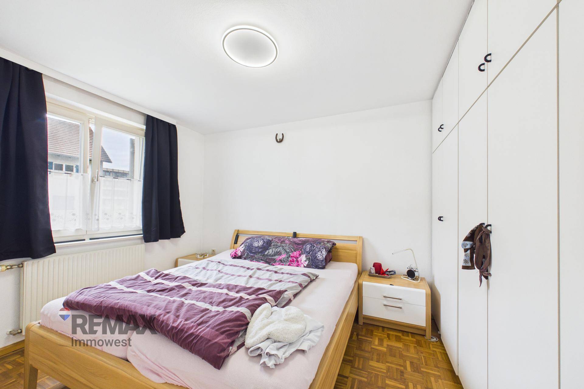 Schlafzimmer mit Doppelbett, Einbauschränken und Parkettboden.