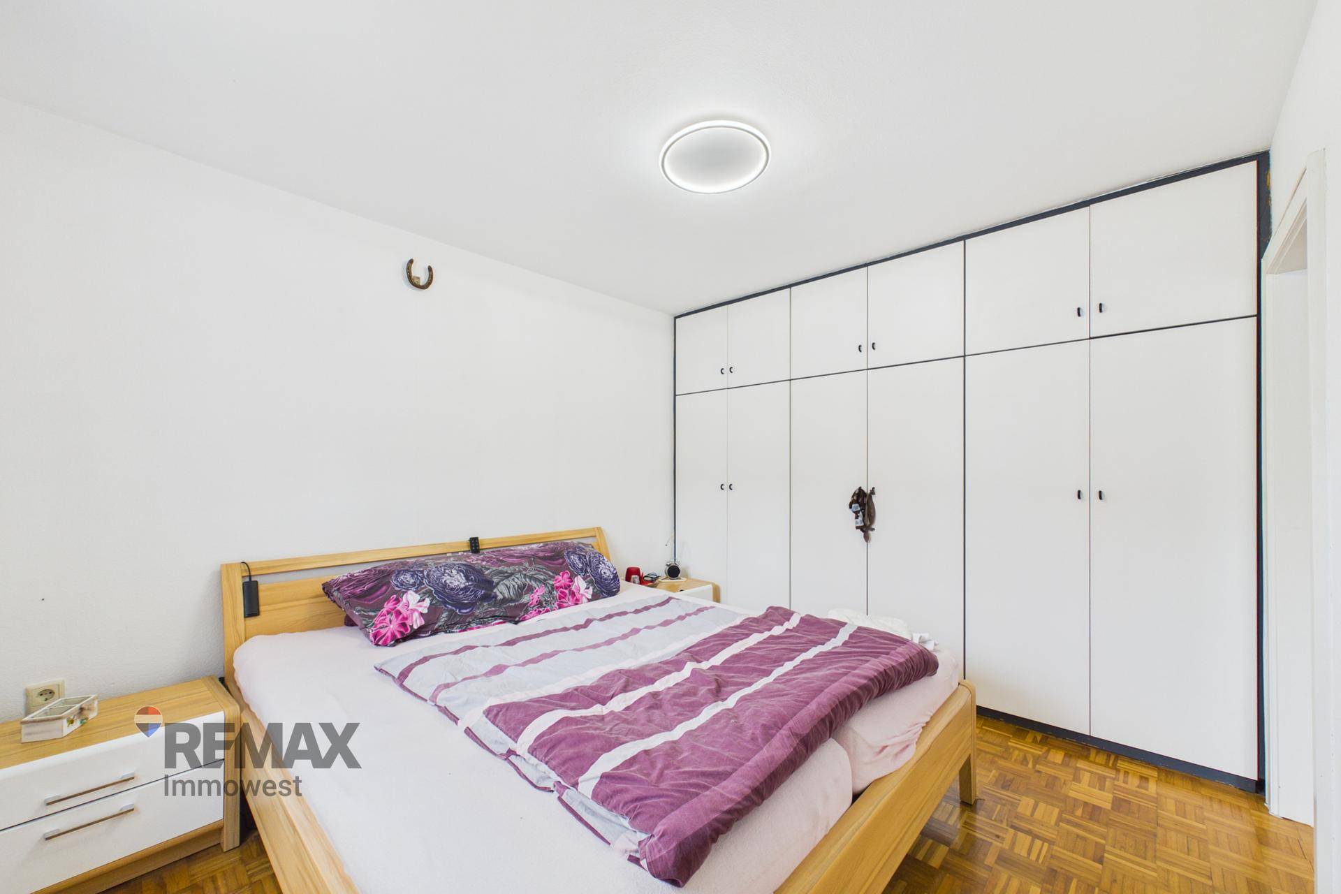 Geräumiges Schlafzimmer mit großer Schrankwand und Parkettboden.