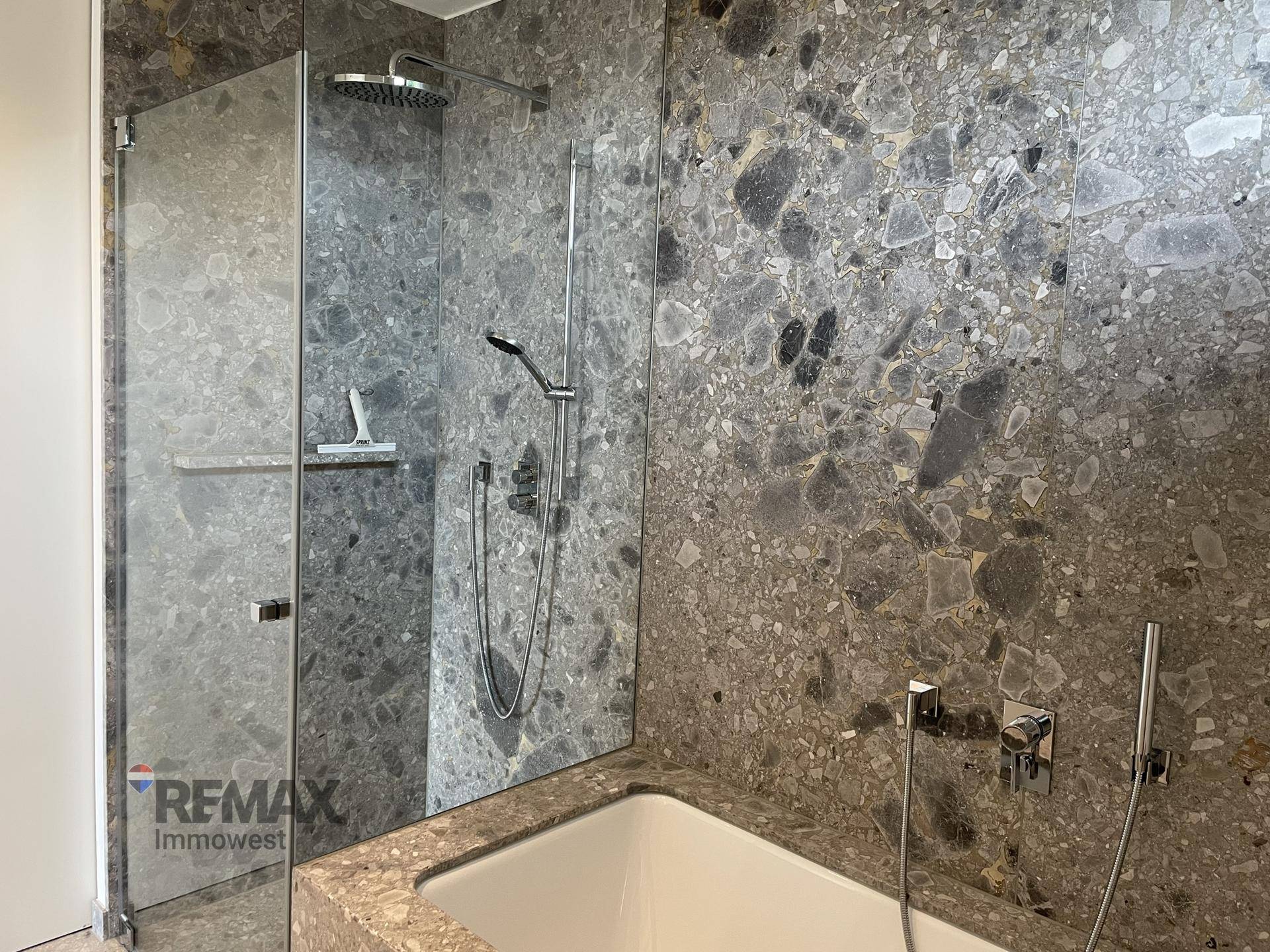 Modernes Badezimmer mit großformatigen Steinfliesen, begehbarer Dusche und Badewanne.