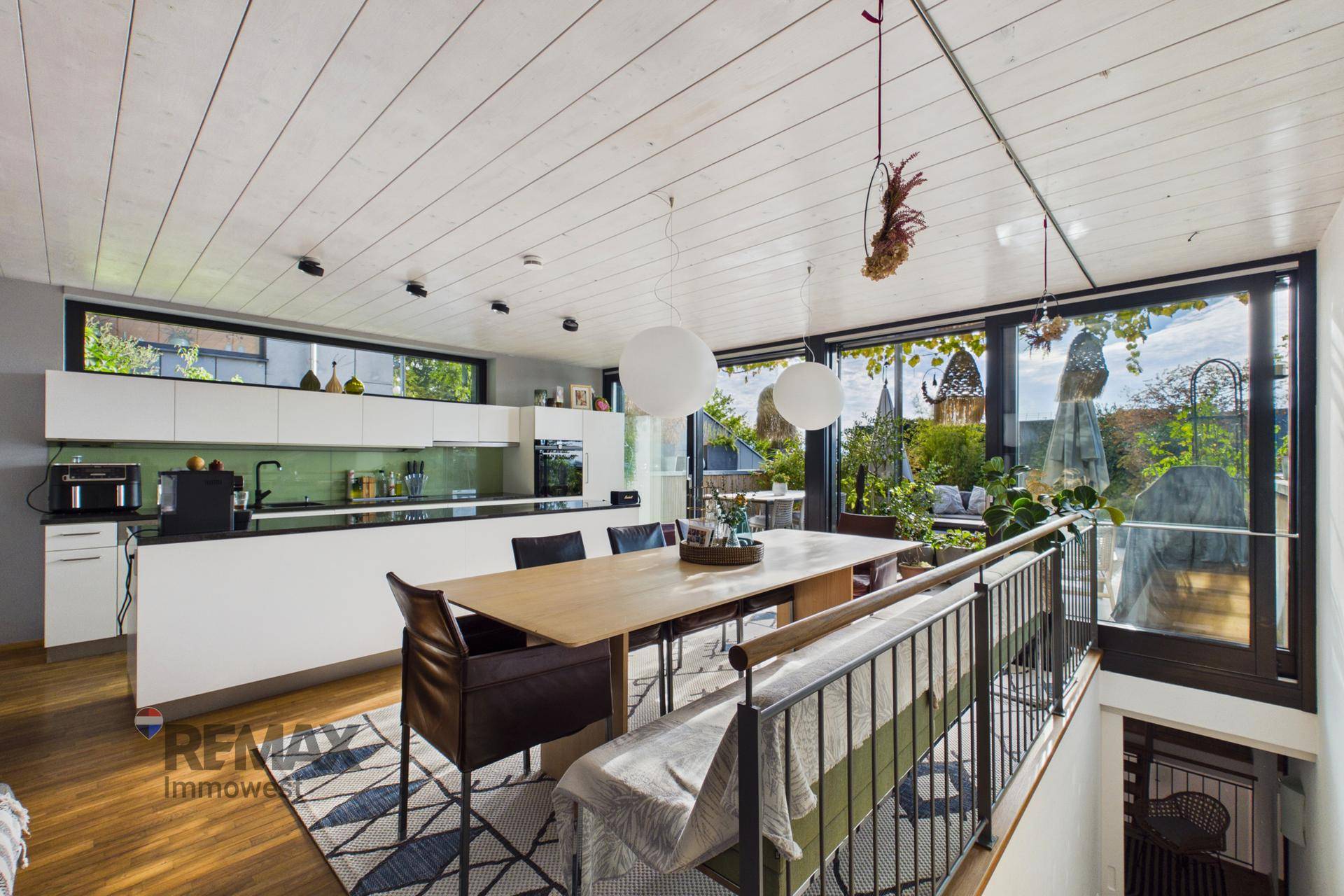 Offener Wohn- und Essbereich mit moderner Küche, Holzboden und Zugang zur Terrasse.