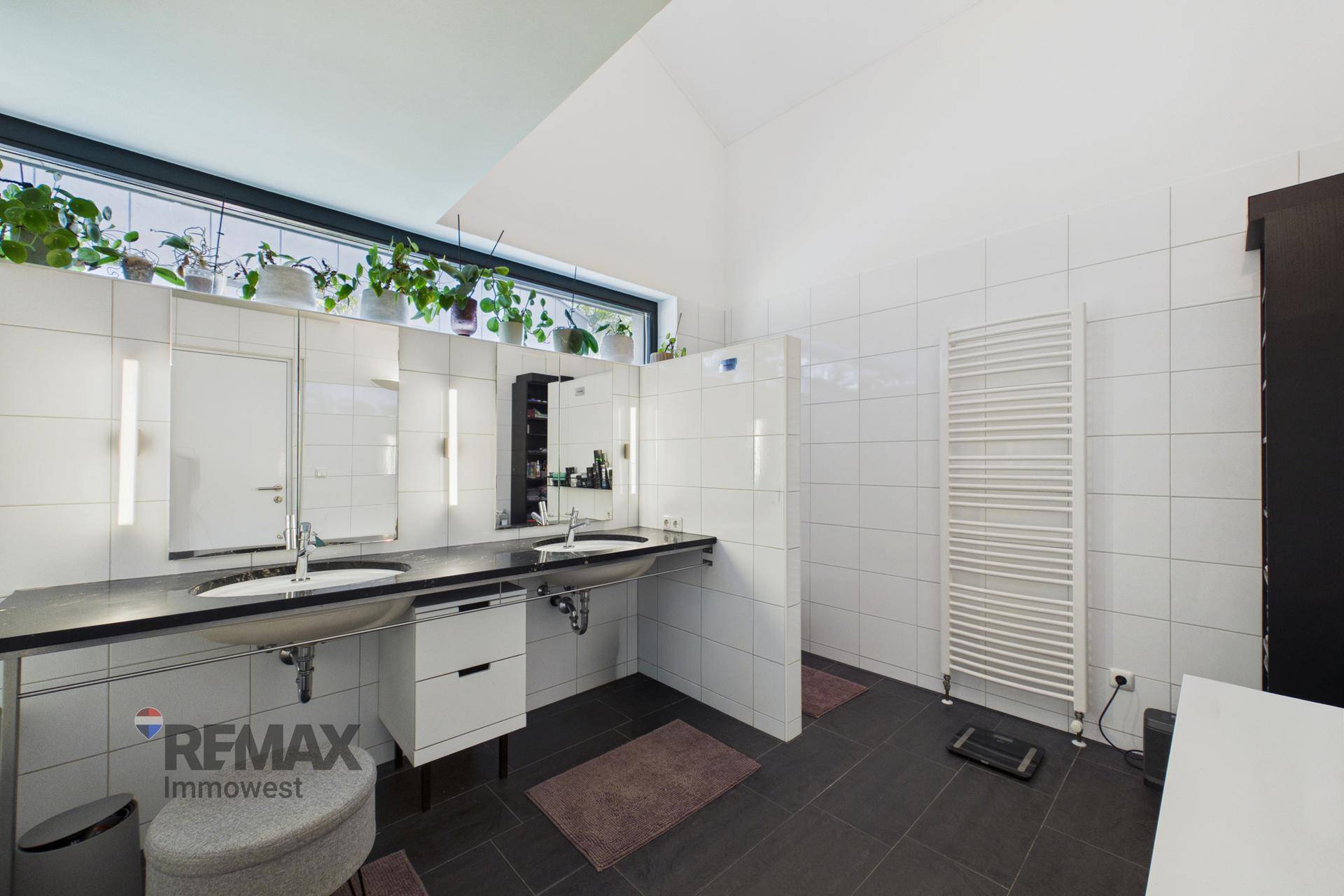 Modernes Badezimmer mit Doppelwaschbecken, Badewanne und großem Fenster für Tageslicht.