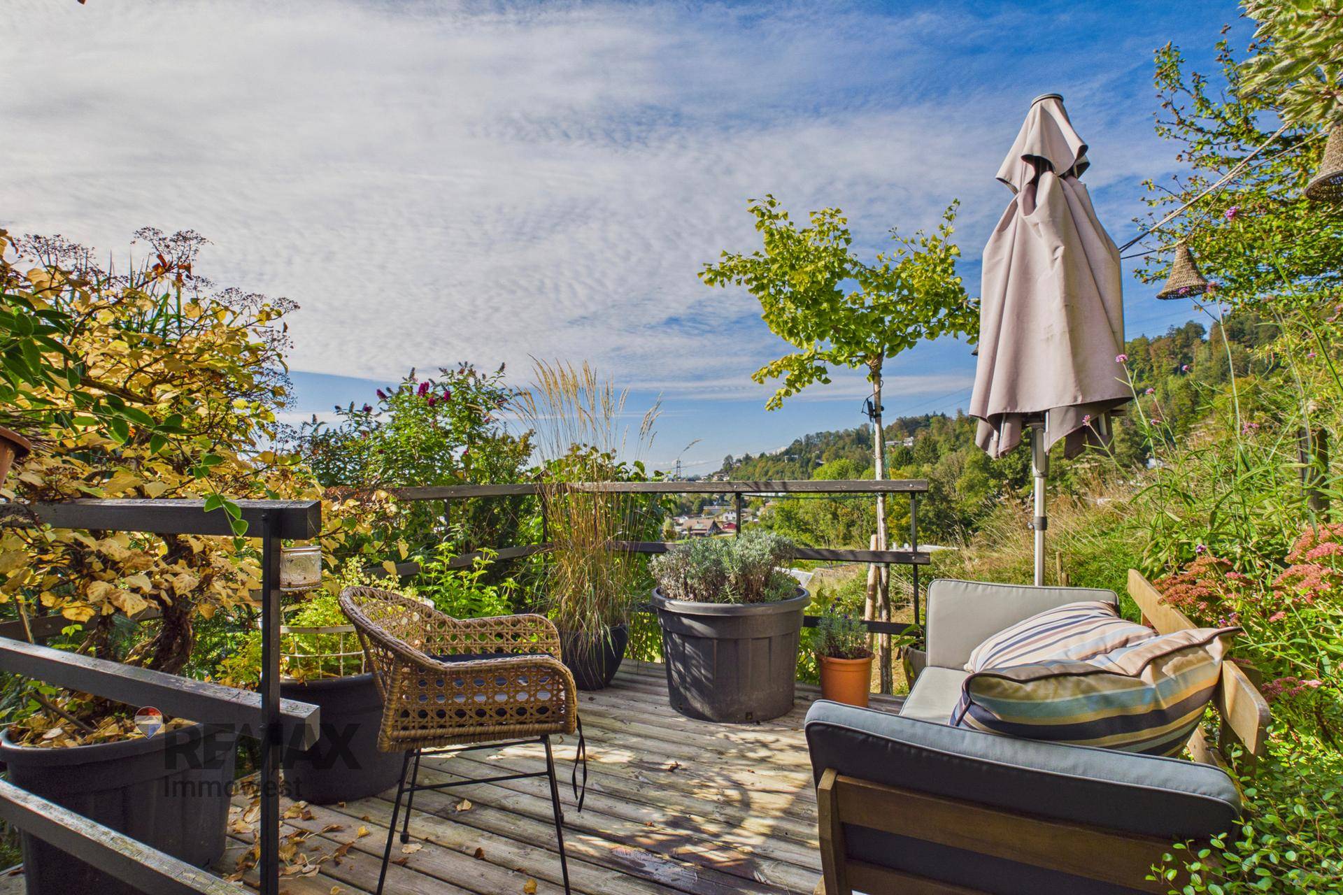 Gemütliche Holzterrasse mit Sitzgelegenheiten, Pflanzen und weitem Blick in die Natur.