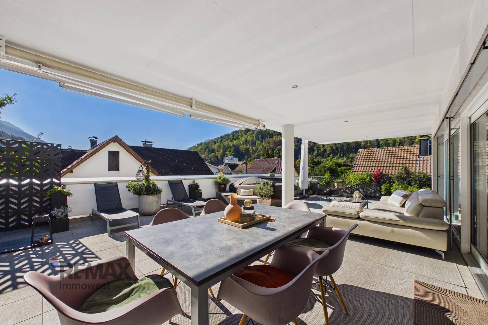 Weitläufige Terrasse mit Essbereich, Liegestühlen und Panoramablick auf die umliegende Berglandschaft.
