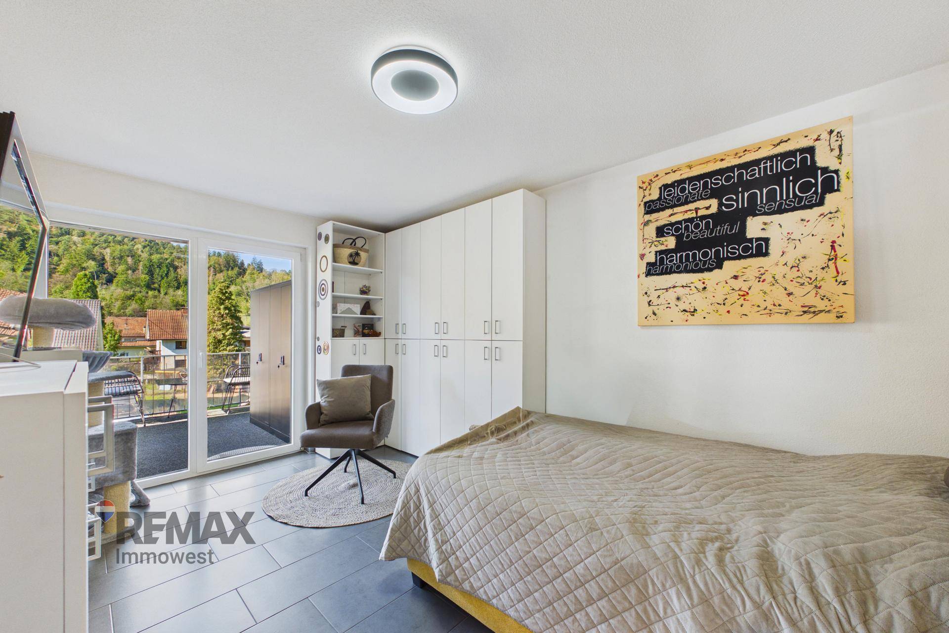 Helles Schlafzimmer mit Zugang zum Balkon, Einbauschränken und Blick auf die grüne Umgebung.