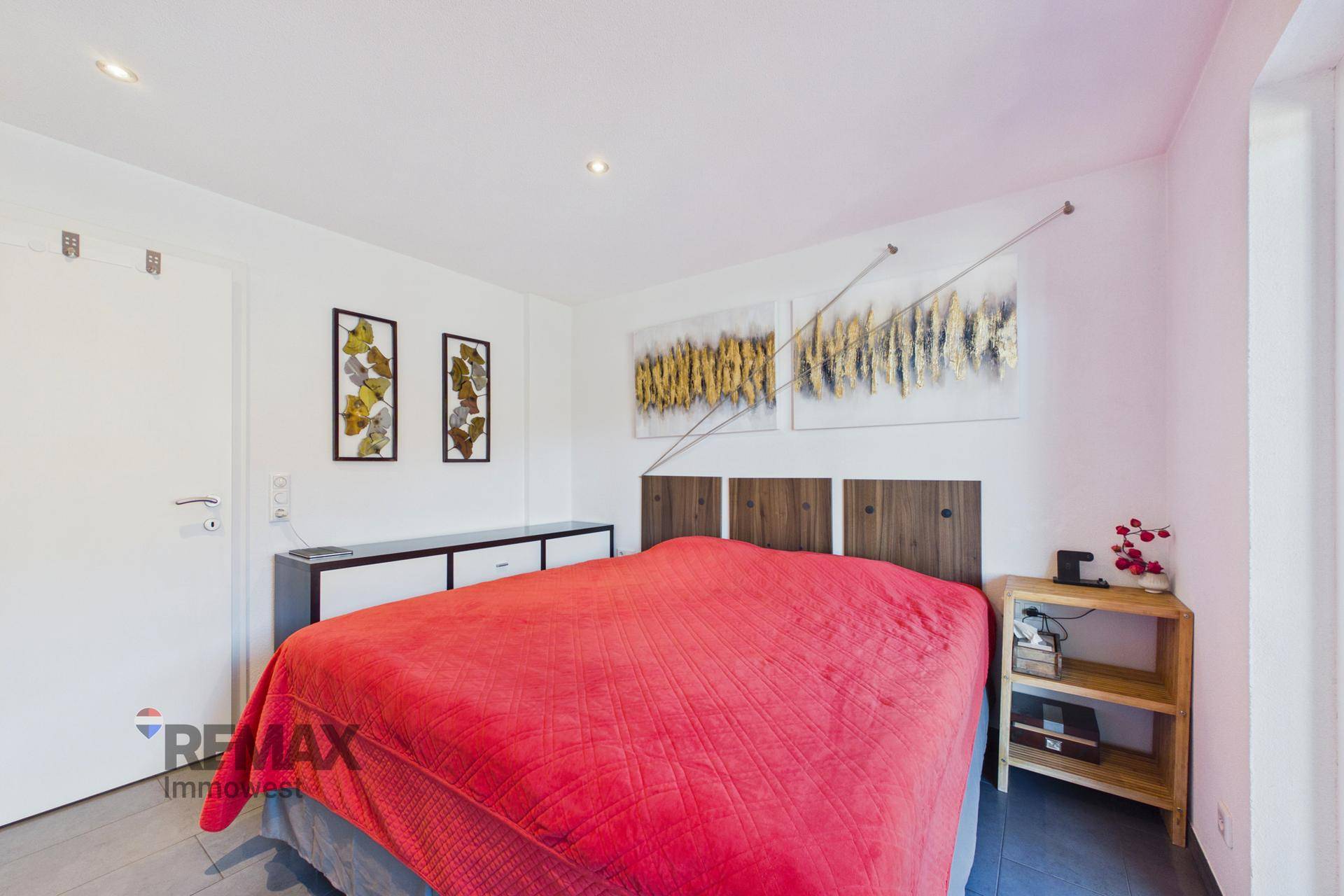 Schlafzimmer mit Doppelbett, modernen Kunstwerken und weißer Einrichtung, bietet eine ruhige Atmosphäre.