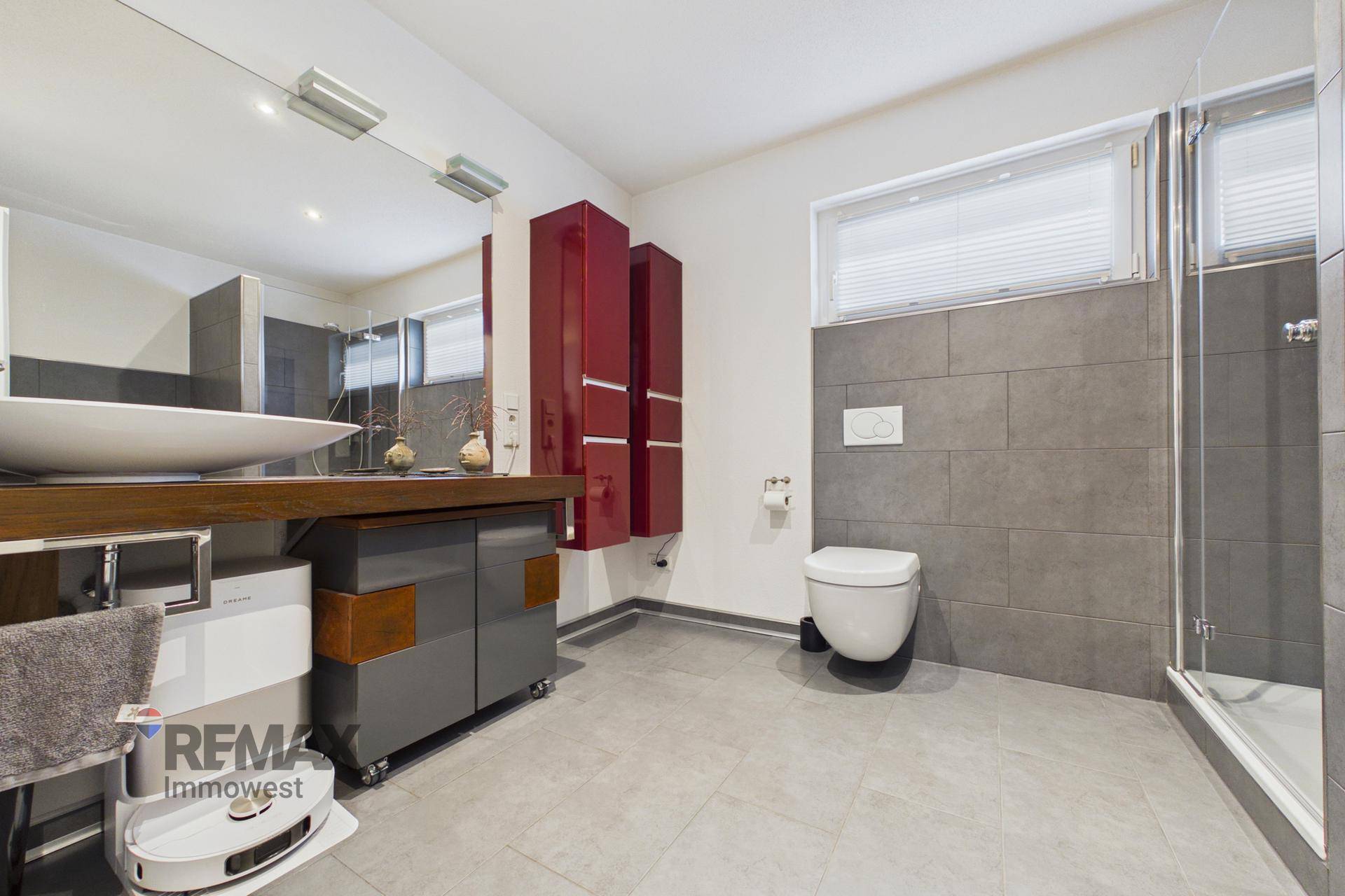 Modernes Badezimmer mit großem Waschbecken, Wand-WC und begehbarer Dusche, in Grautönen gehalten.