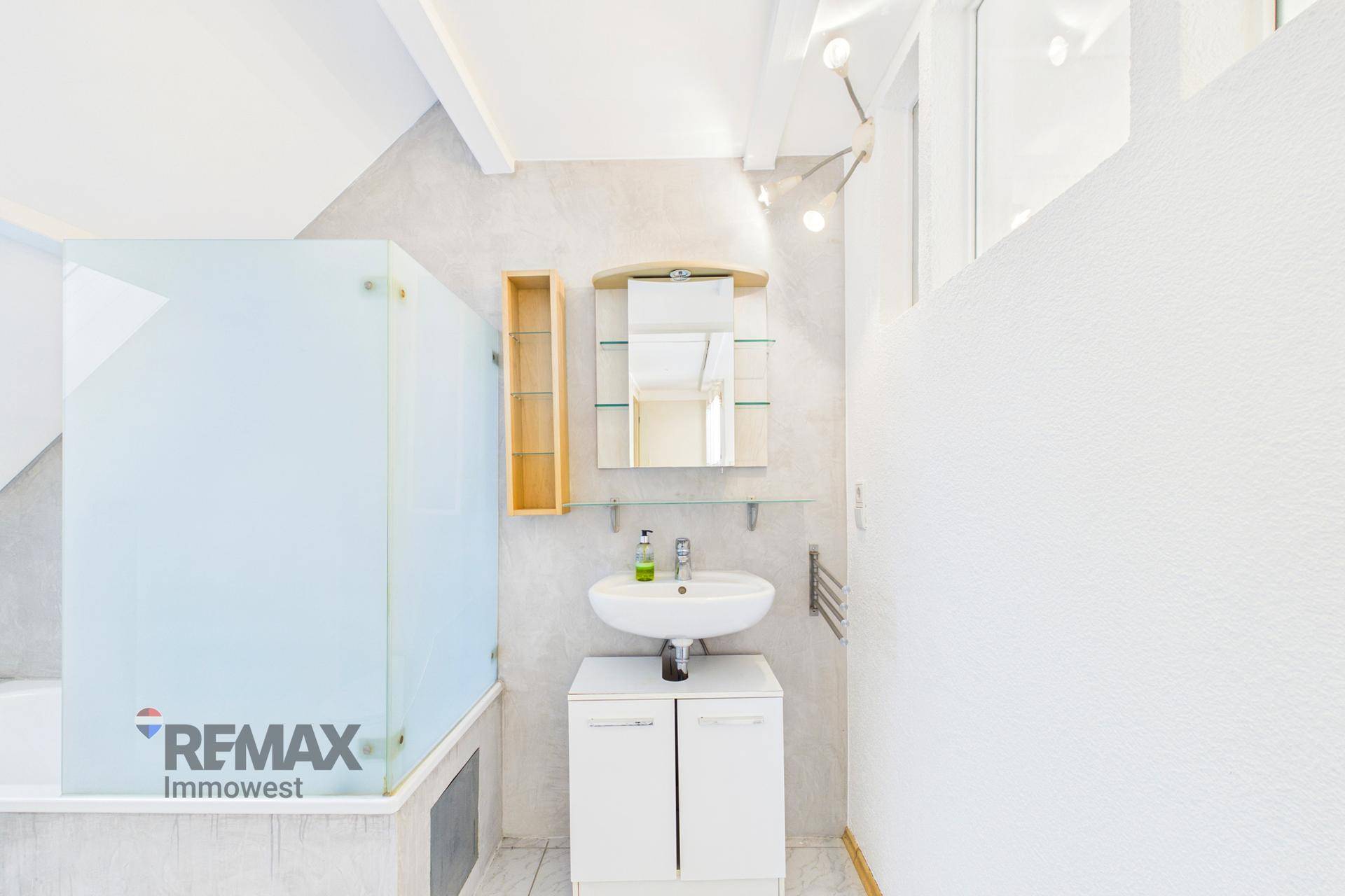 Modernes Badezimmer mit Duschbereich, Waschbecken und Spiegelschrank, mit Handtuchheizkörper.