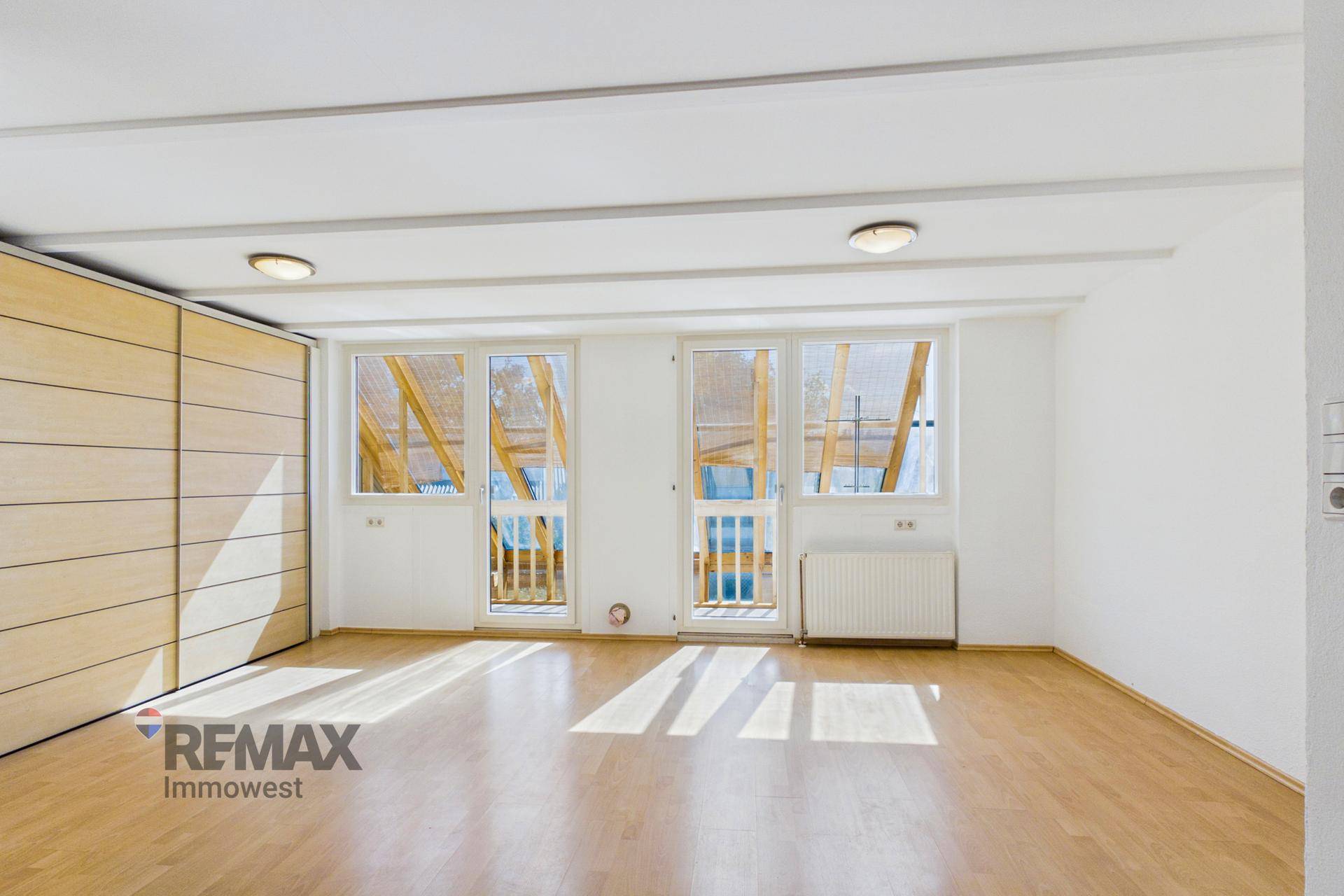Heller Raum mit Holzboden, Einbauschränken und Zugang zu einem französischen Balkon, sehr einladend.