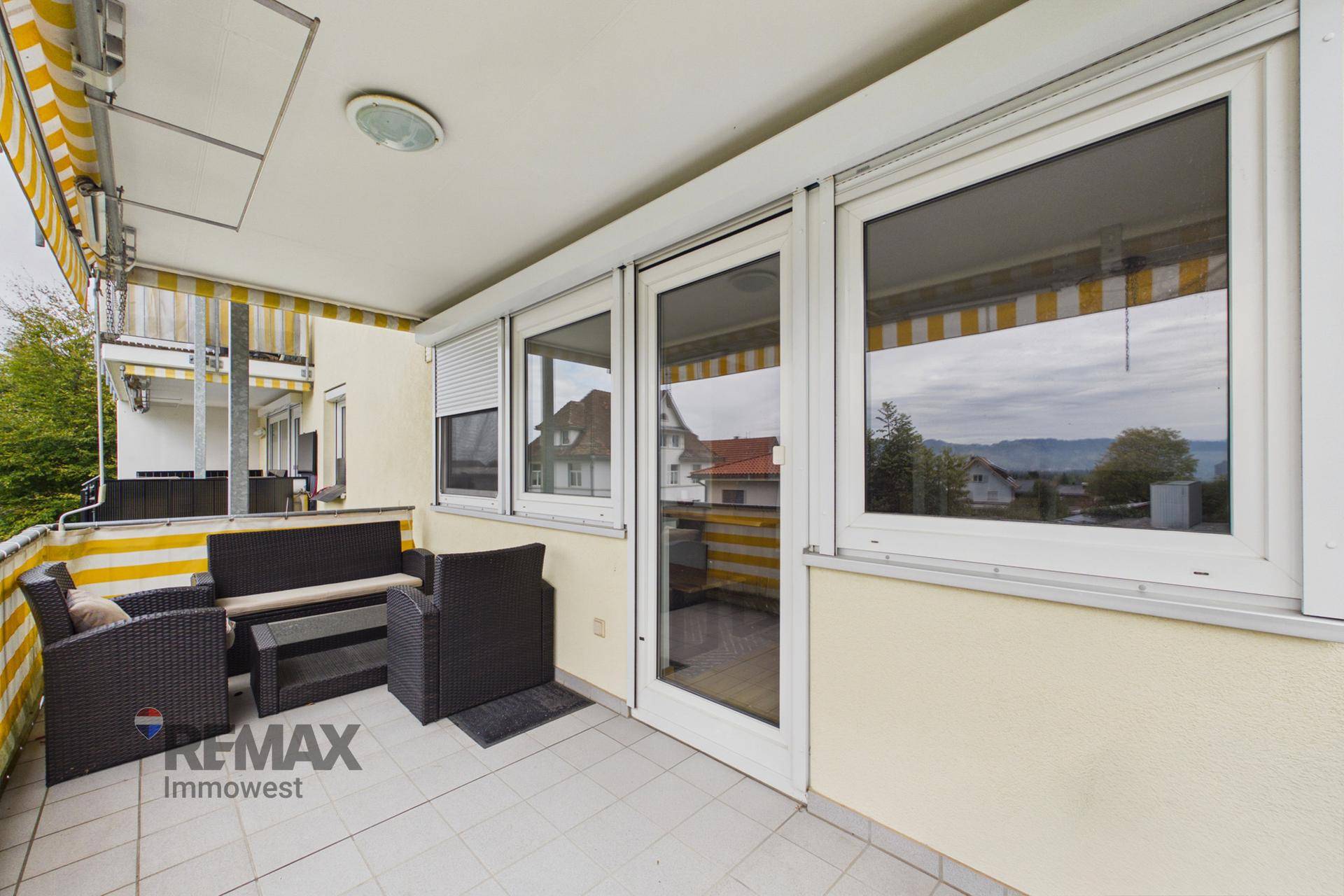 Balkon mit Sitzgelegenheiten, Markise und Blick auf die Umgebung.