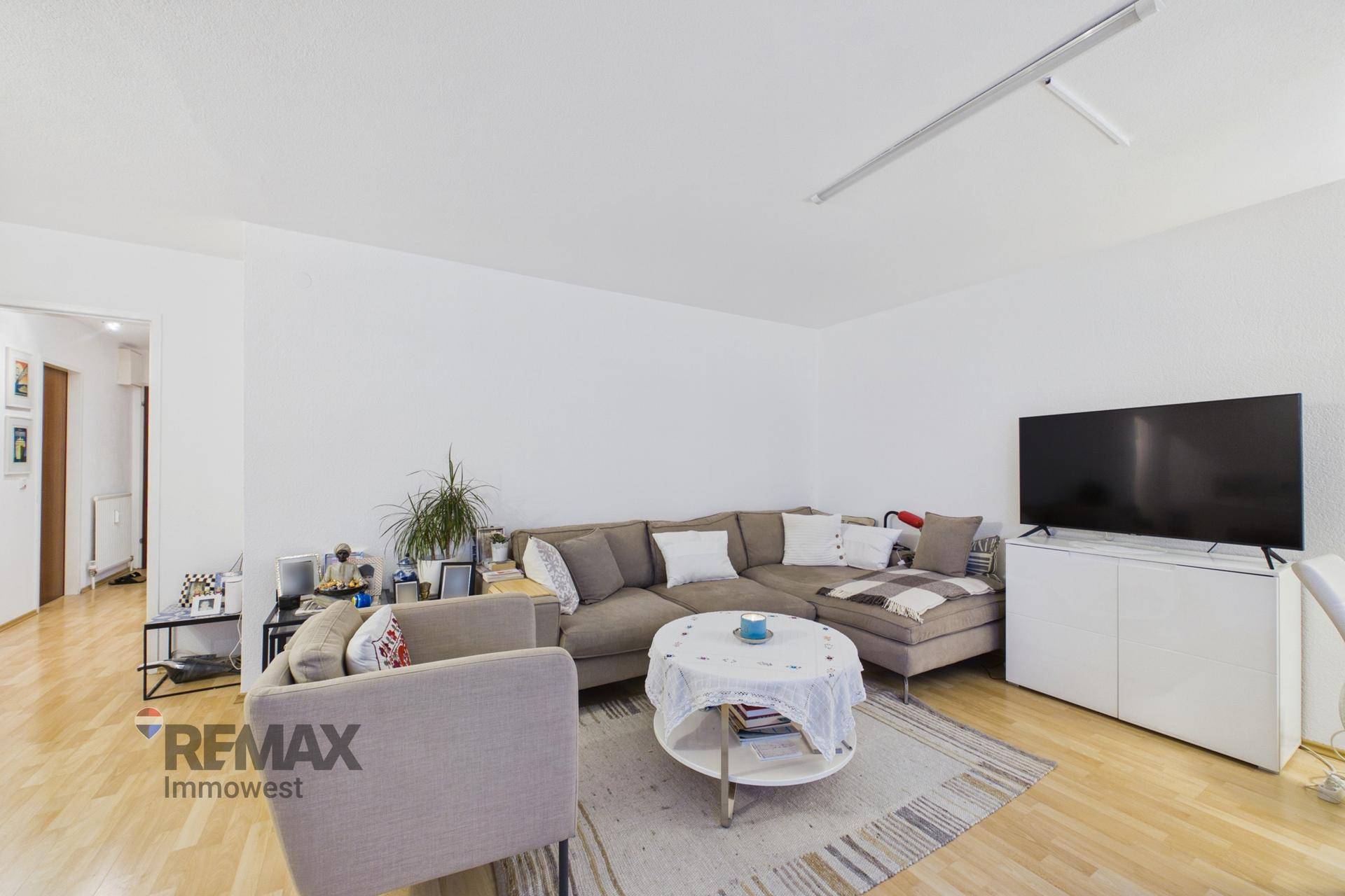 Heller Wohnbereich mit großem Ecksofa, Couchtisch und Fernseher auf Holzfußboden.