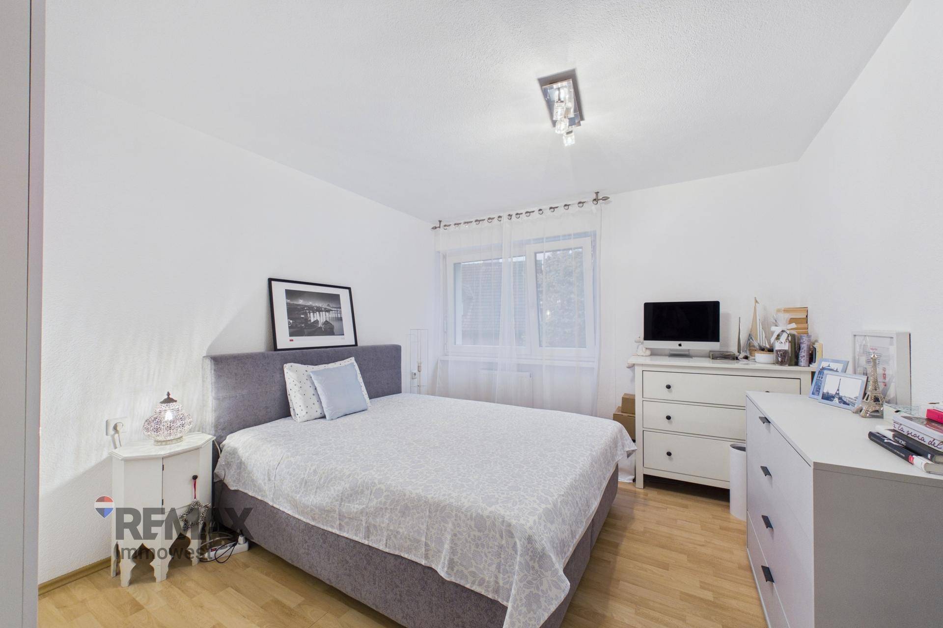 Gemütliches Schlafzimmer mit Doppelbett, Holzfußboden und Fenster für natürliches Licht.