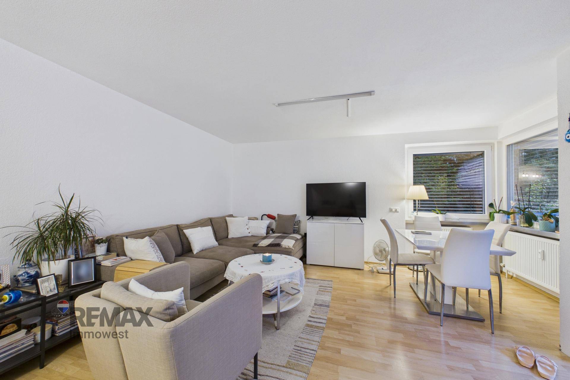 Offener Wohn- und Essbereich mit Sofa, Esstisch und großen Fenstern für viel Licht.