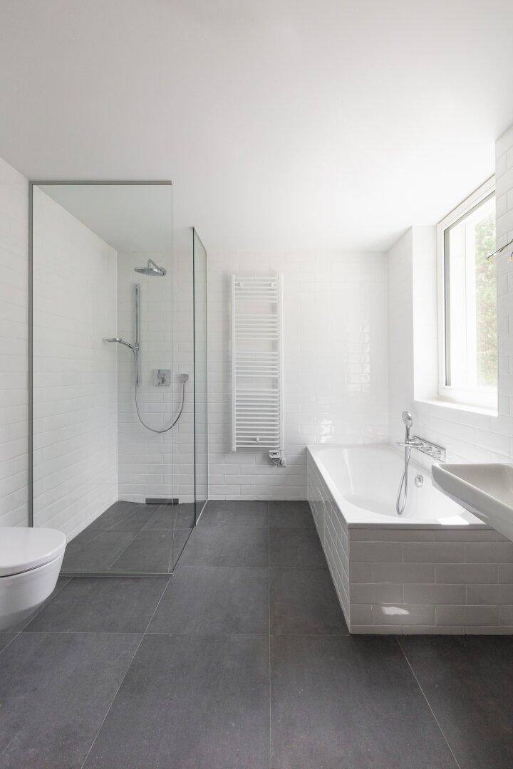Helles, modernes Badezimmer mit großer begehbarer Dusche, Badewanne und Handtuchheizkörper.