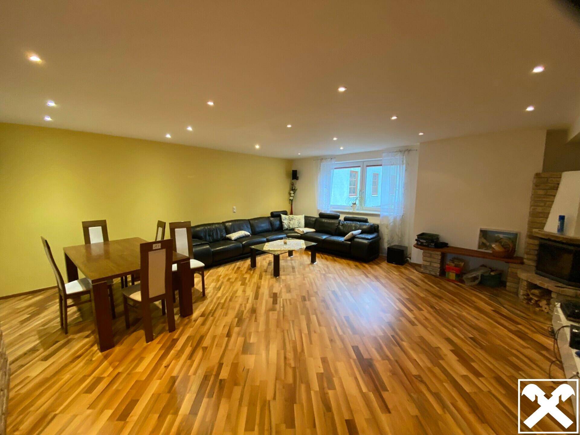 Geräumiges Wohn-Esszimmer mit Holzboden, Kamin und moderner Einrichtung.