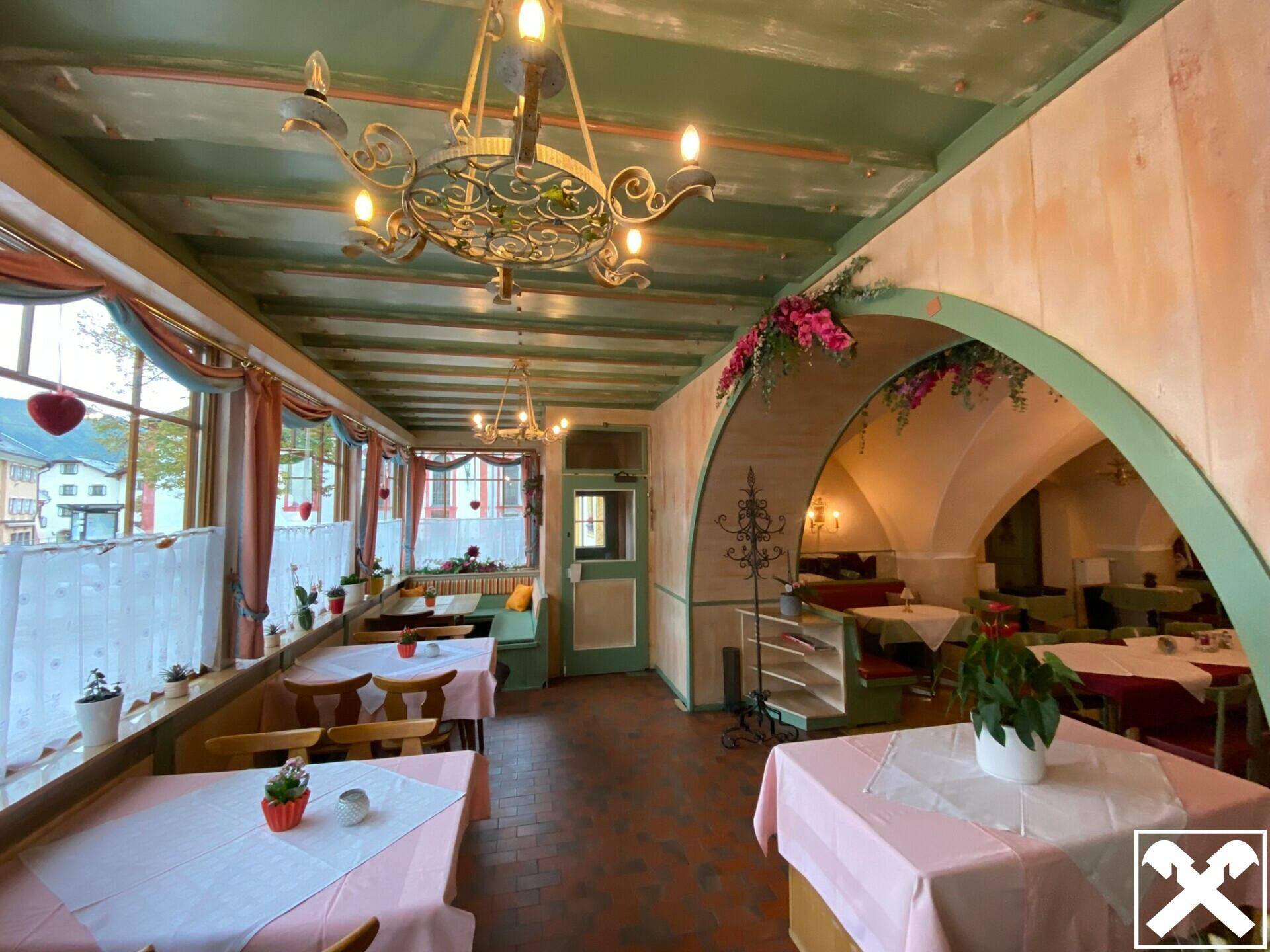 Gemütlicher Restaurantbereich mit Holzbalkendecke, traditionellen Möbeln und Blick nach draußen.