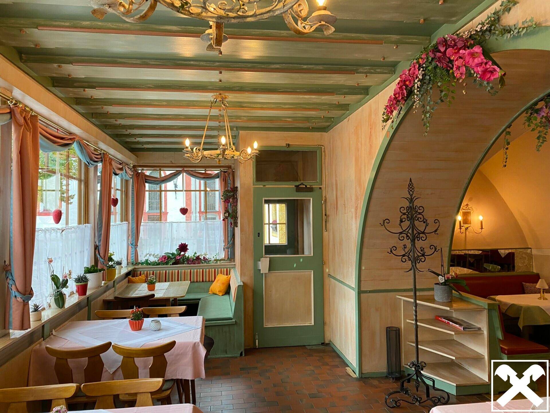 Traditioneller Restaurantbereich mit Holzbalkendecke, rustikalen Möbeln und floraler Dekoration.