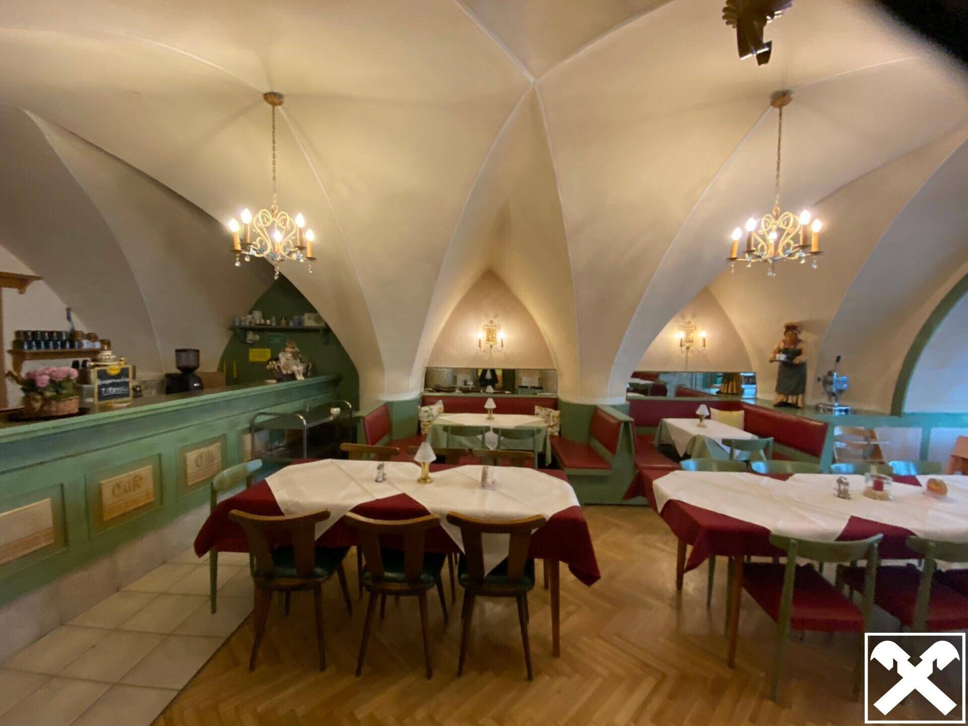 Großer Restaurantbereich mit beeindruckenden Gewölbedecken, Kronleuchtern und Holzboden.