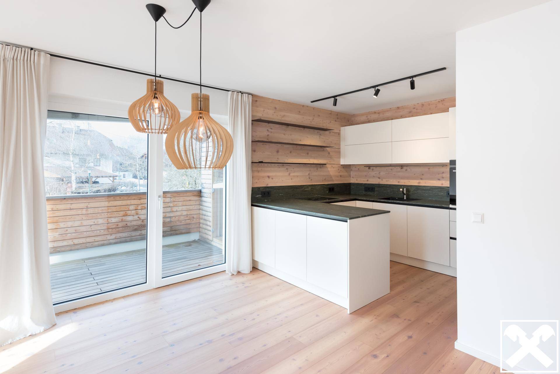 Moderne offene Küche mit weißen Schränken, Holzakzenten und direktem Zugang zur Terrasse.