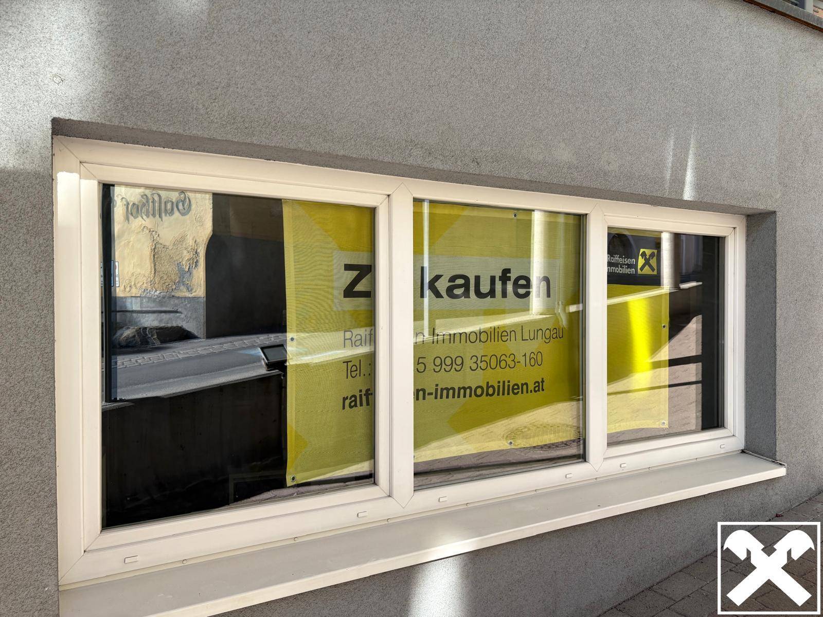 Außenansicht eines Fensters mit "Zu kaufen" Beschriftung, das auf die Verfügbarkeit der Immobilie hinweist.