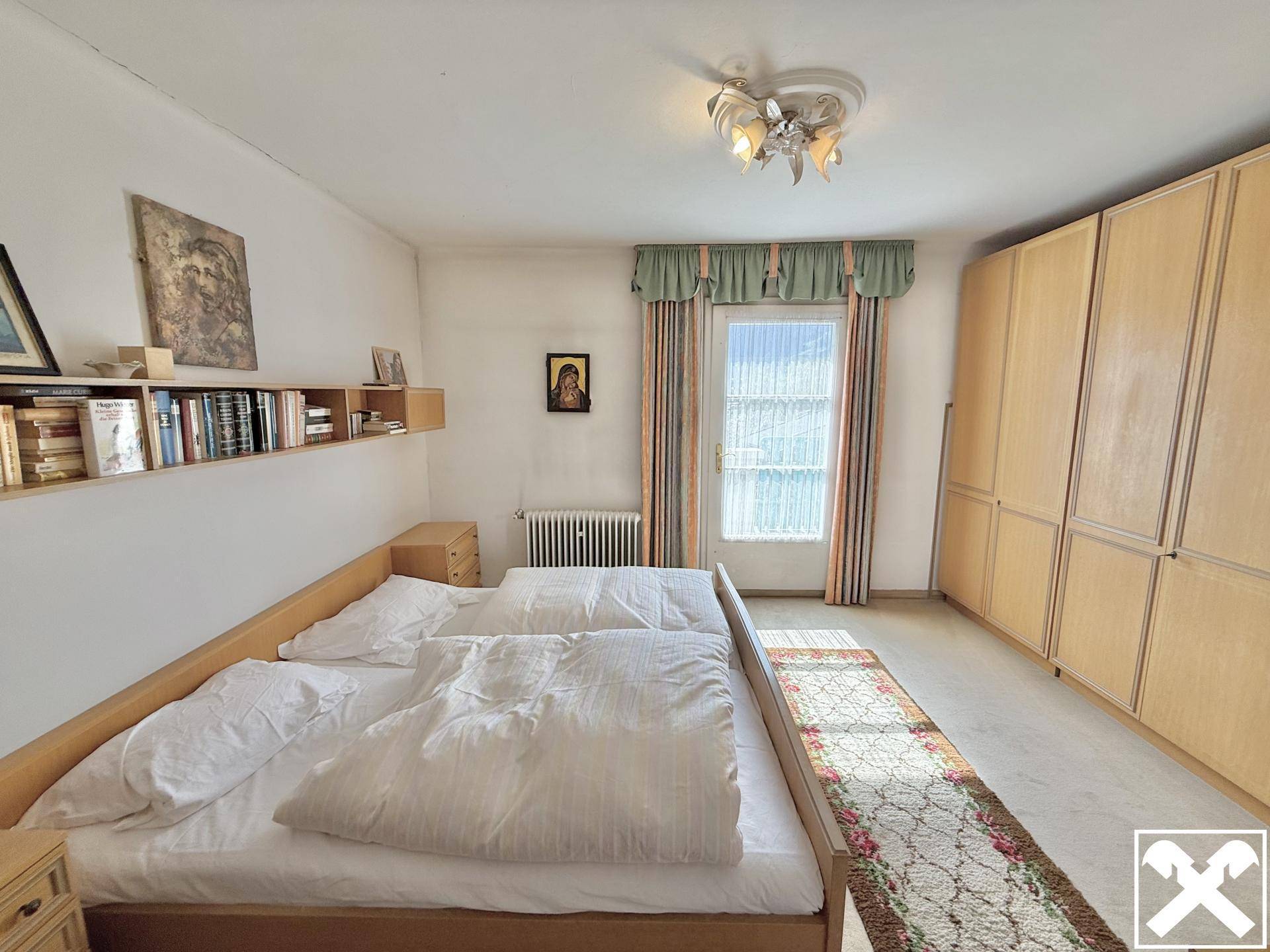 Helles Schlafzimmer mit zwei Einzelbetten, Einbauschränken und einem Fenster für natürliche Belichtung.