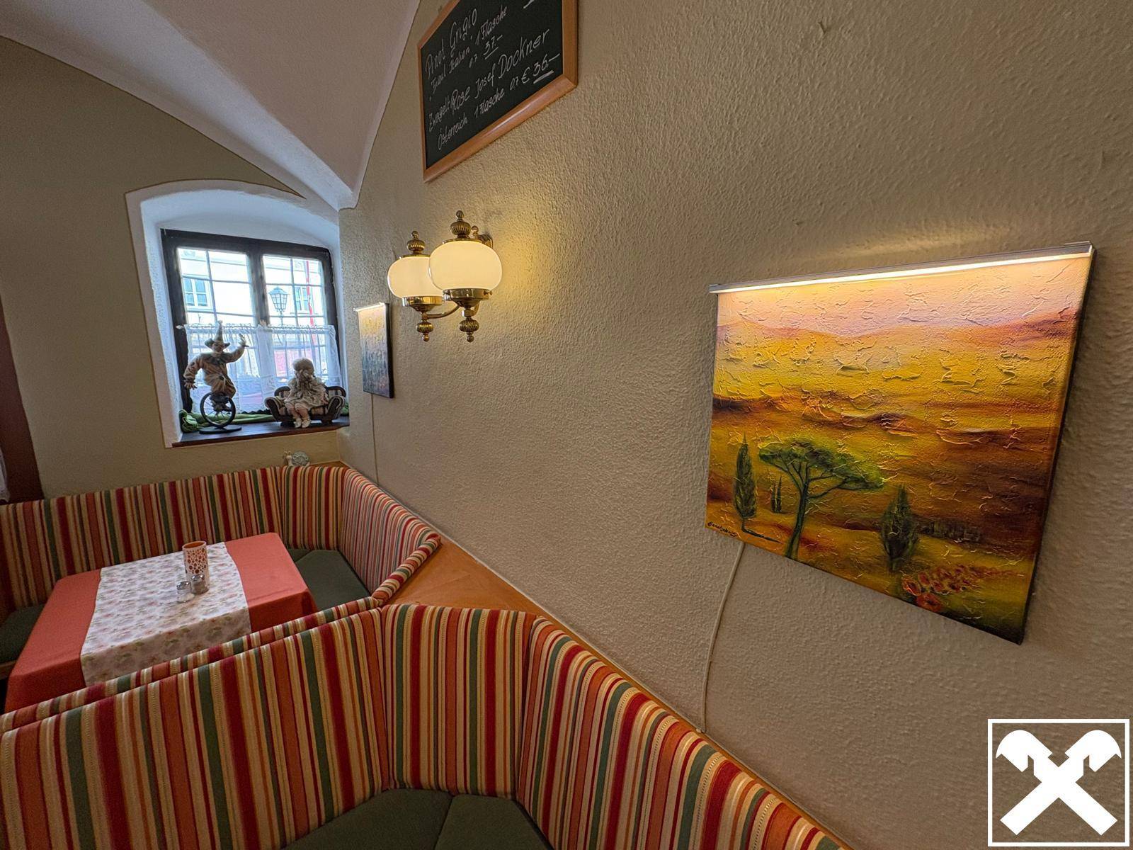 Gemütliche Sitzecke im Restaurant mit gestreiften Polstern und einem Fenster mit Blick nach draußen.
