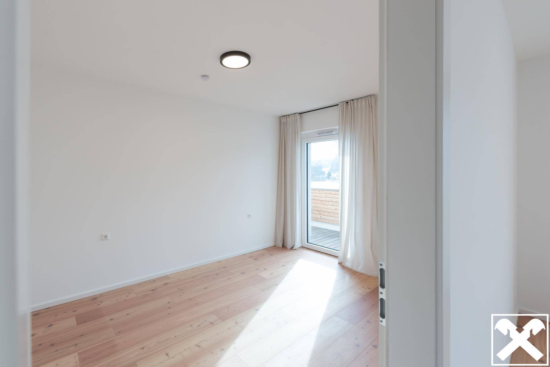 Helles Schlafzimmer mit Holzboden und direktem Zugang zu einem Außenbereich.