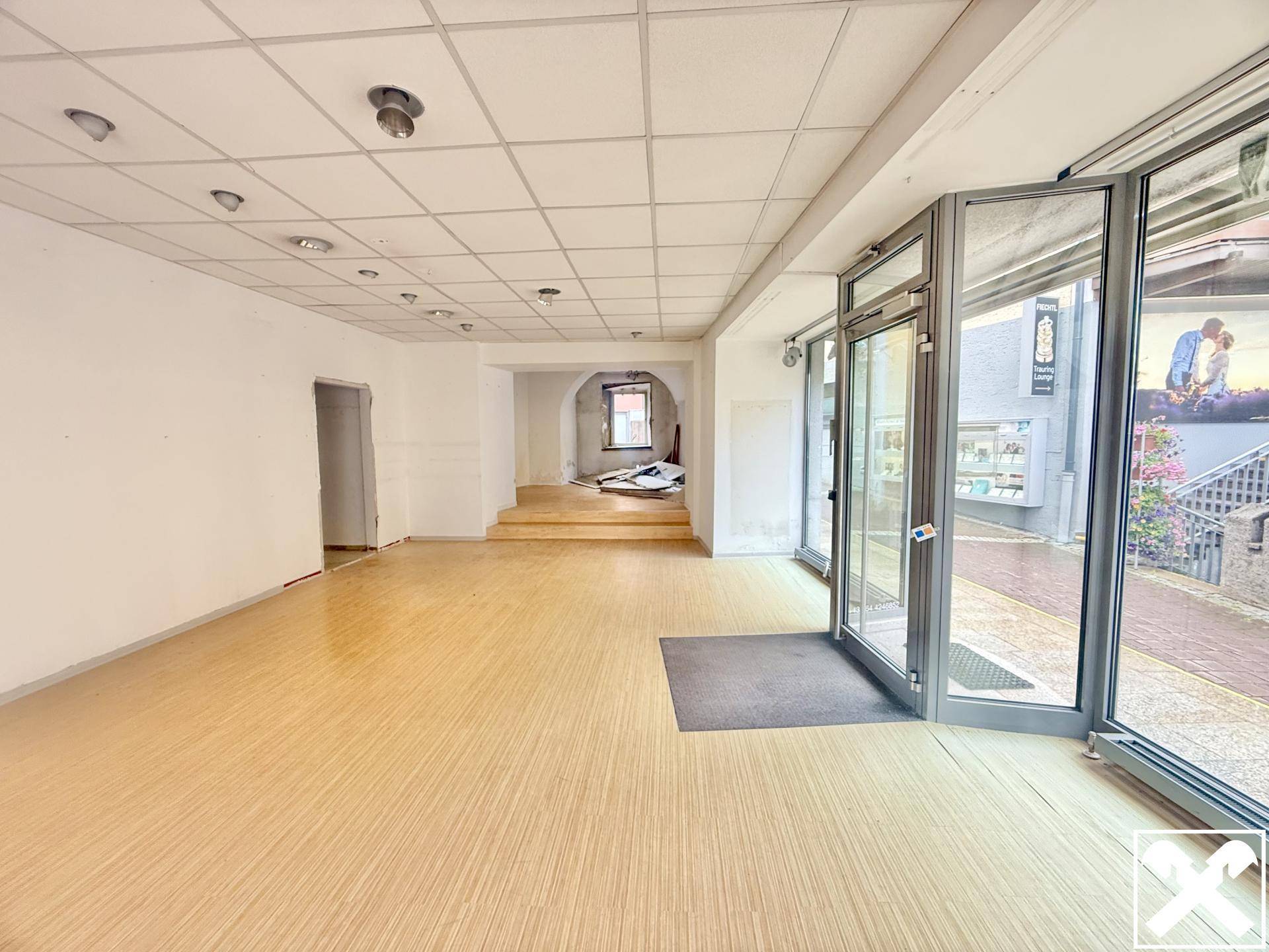 Großer, heller Raum mit Laminatboden und großen Glasfronten, die viel Tageslicht hereinlassen.