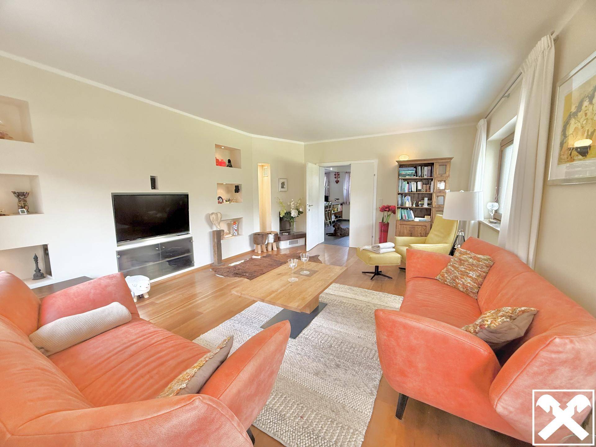 Gemütliches Wohnzimmer mit zwei orangefarbenen Sofas und dekorativen Wandnischen.