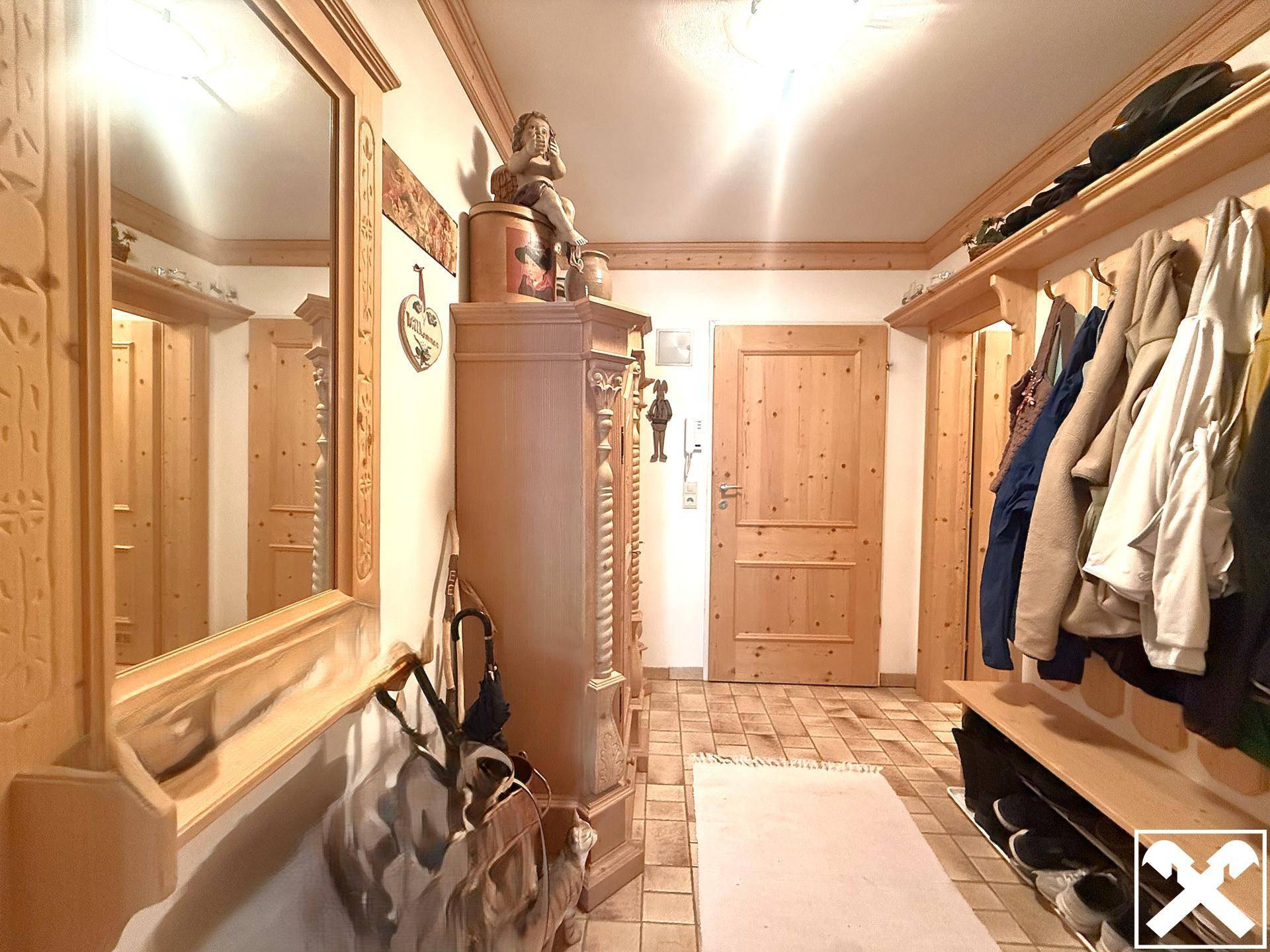 Eingangsbereich mit Holzmöbeln, großem Spiegel und Garderobe für Kleidung.