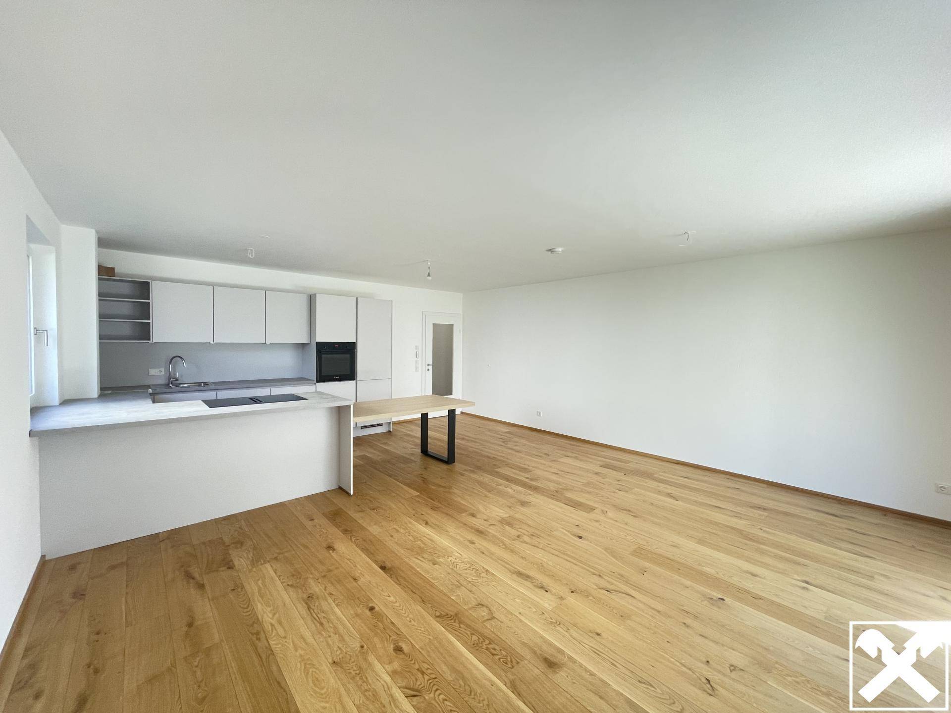 Heller, offener Wohnbereich mit moderner Einbauküche, Holzboden und viel Tageslicht.