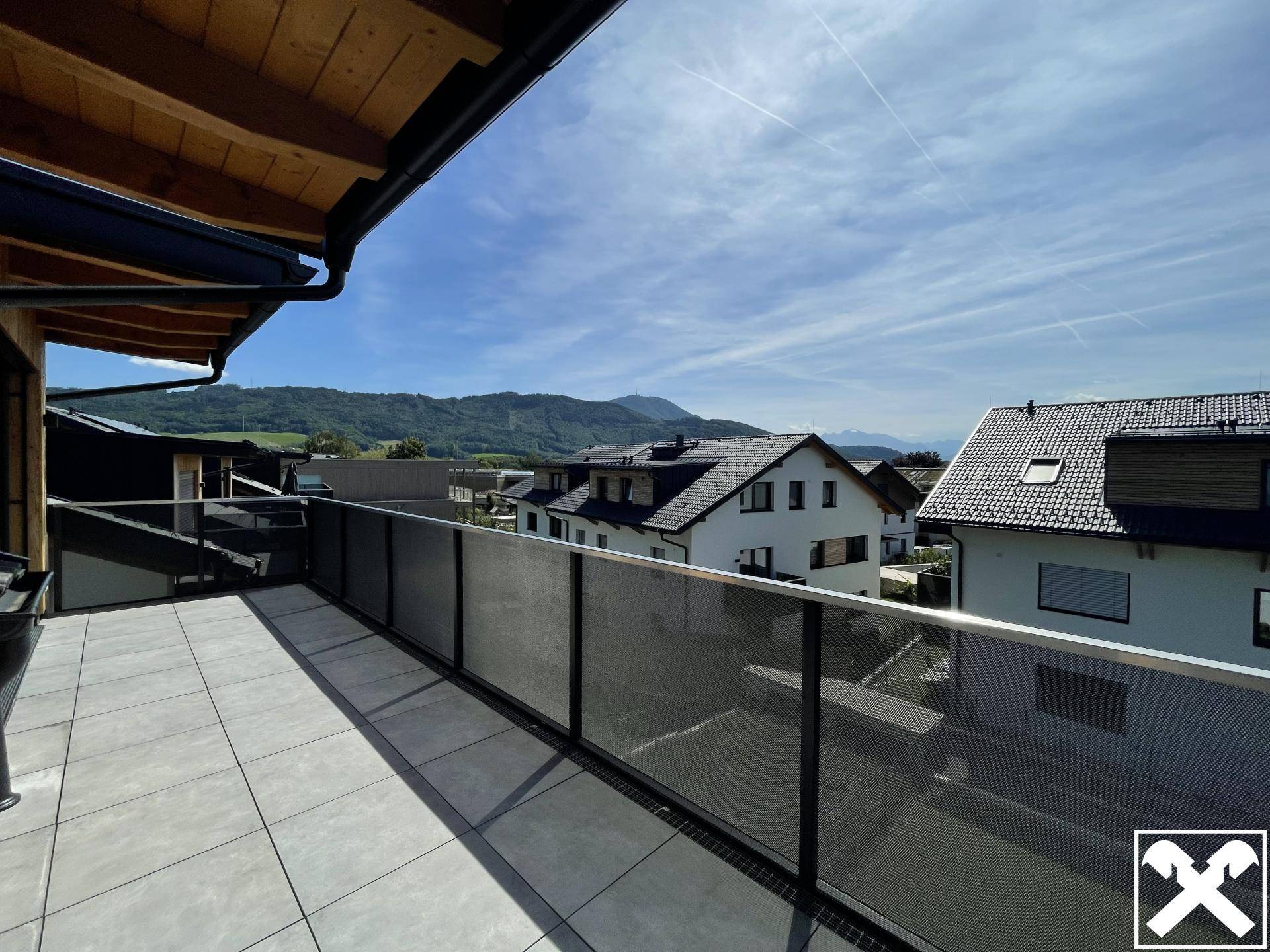 Geräumiger Balkon mit Fliesenboden und modernem Geländer bietet einen weiten Bergblick.