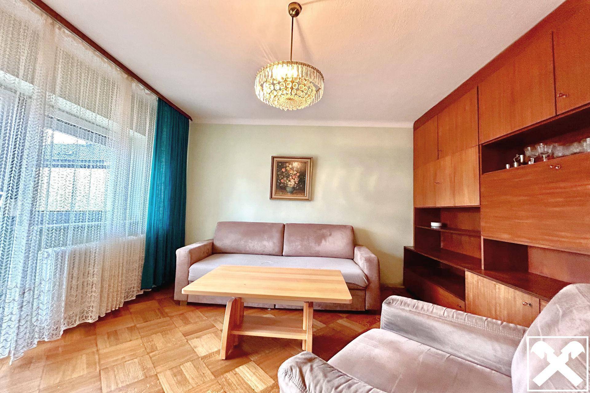 Gemütliches Wohnzimmer mit Sofa, Holzelementen und einem Kronleuchter, ideal zum Entspannen.