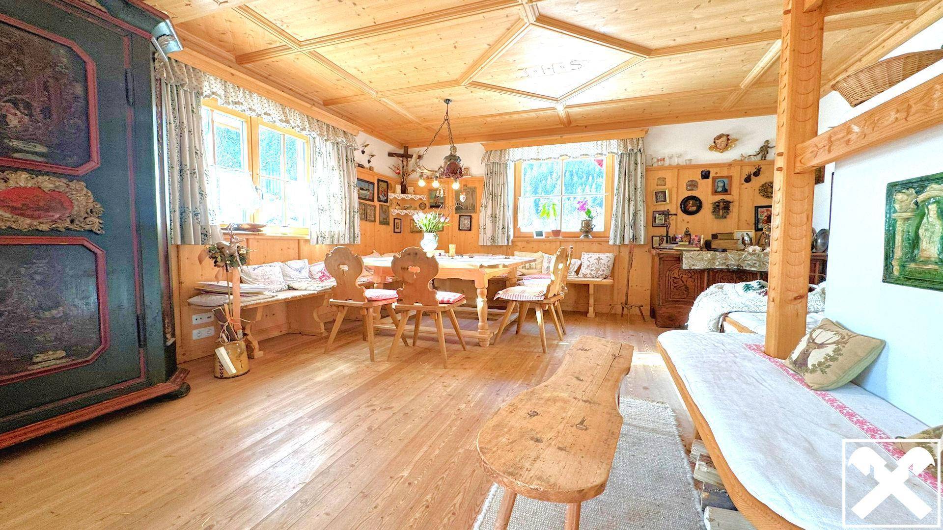 Traditionelle Stube mit Holztäfelung, Esstisch und Sitzbänken, typisch für den alpinen Stil.
