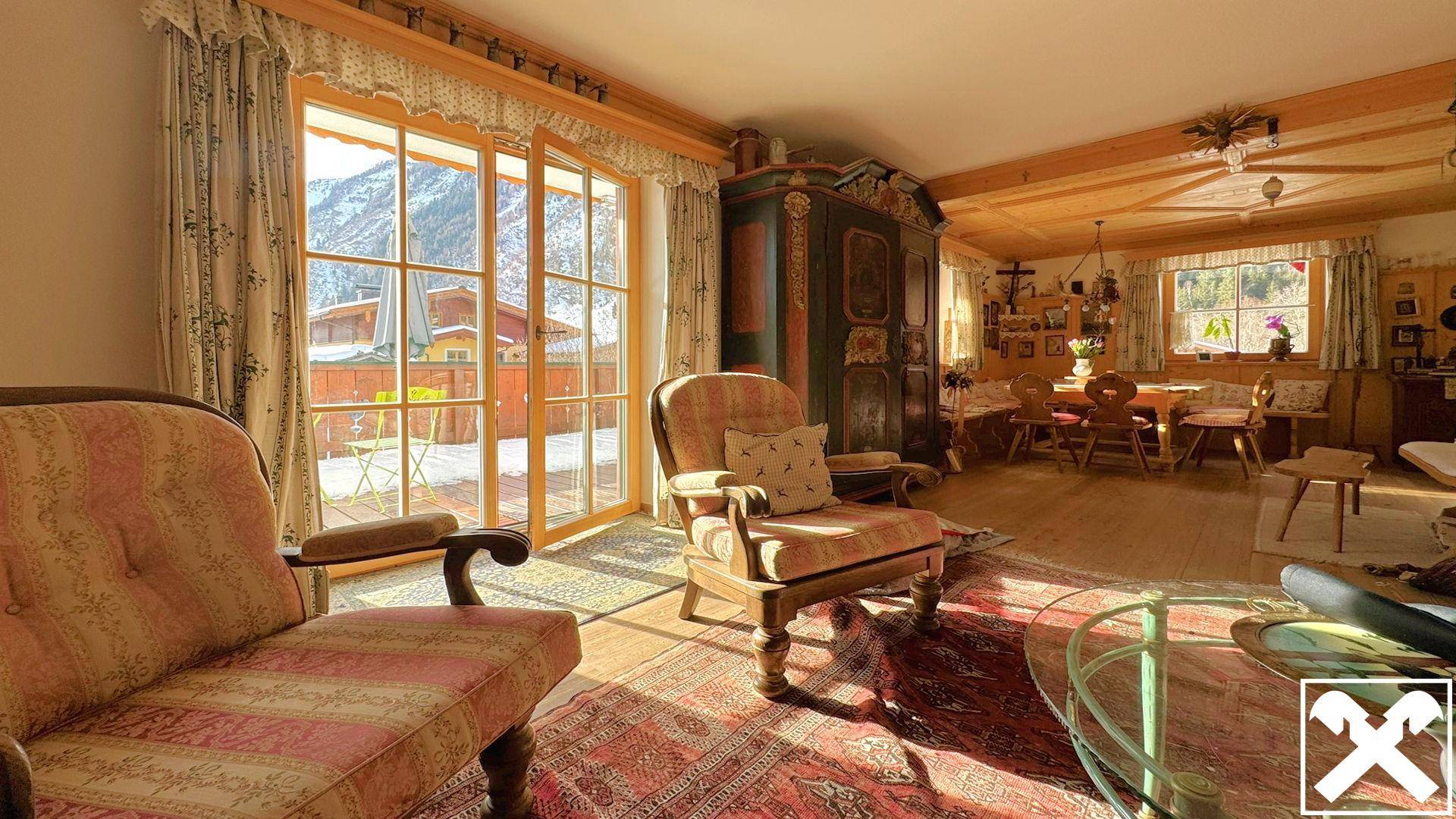 Gemütliches Wohnzimmer im Alpenstil mit Holzbalkendecke, traditionellen Möbeln und Bergblick.
