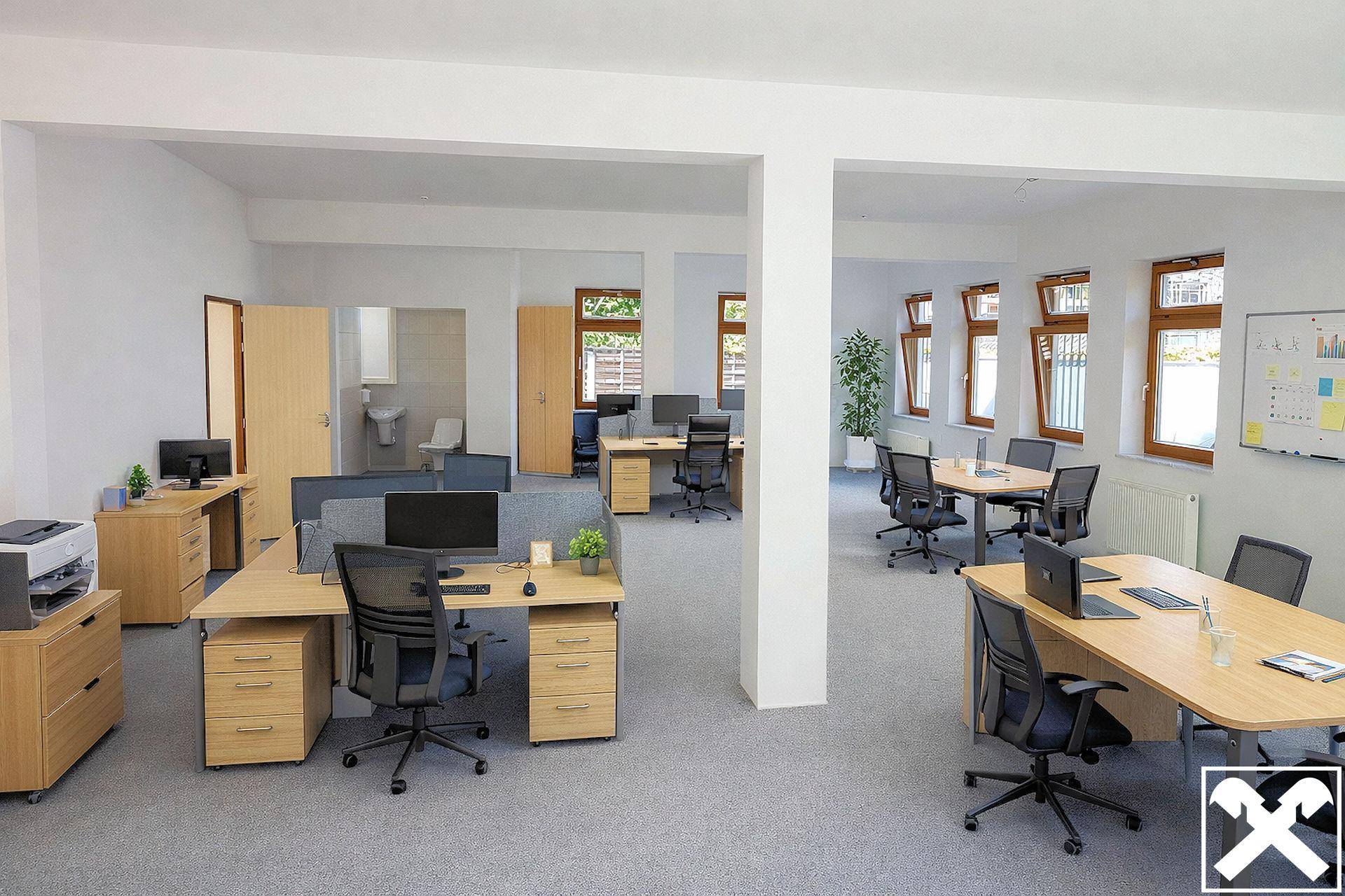 Geräumiges Großraumbüro mit mehreren Arbeitsplätzen, Konferenztisch und natürlichem Lichteinfall durch große Fenster.