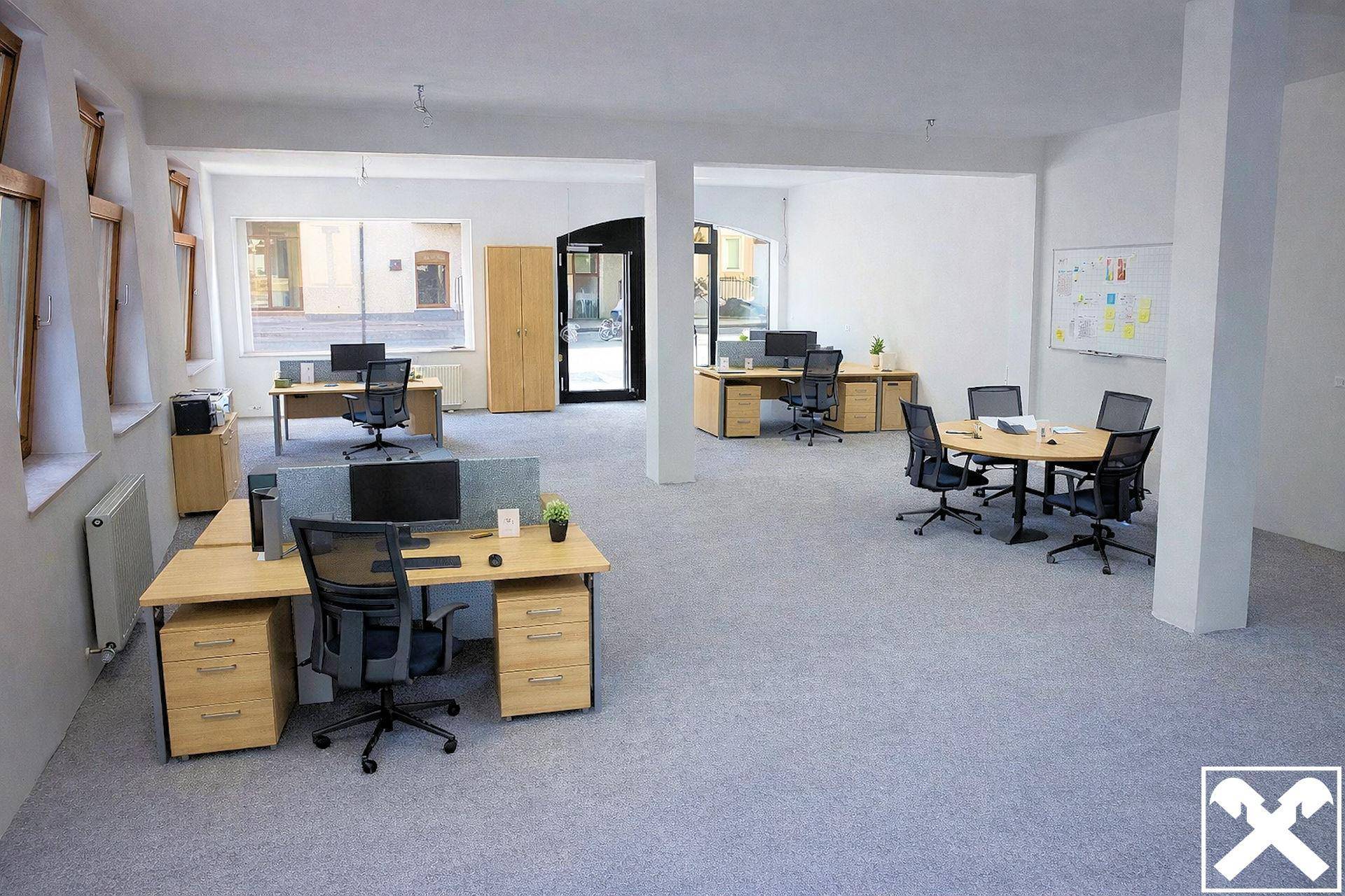 Helles und offenes Büro mit mehreren Schreibtischen und einem Besprechungsbereich, ideal für Teamarbeit.