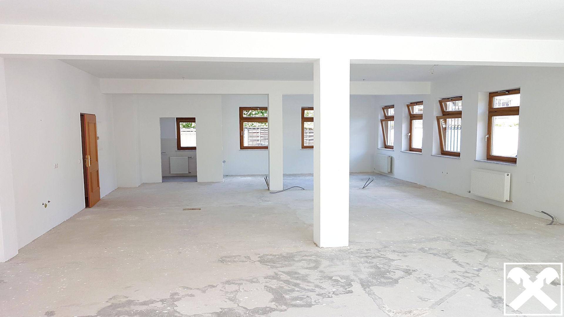 Leerer, unmöblierter Raum mit Betonboden und weißen Wänden, bereit für den Innenausbau oder die Nutzung.