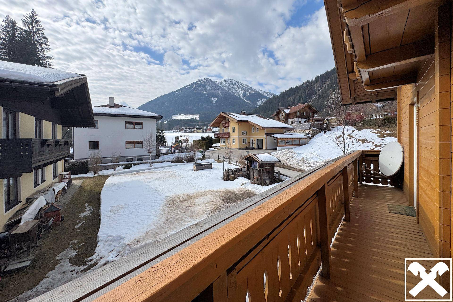Balkon mit Holzboden und Geländer bietet einen weiten Blick auf die verschneite Berglandschaft.