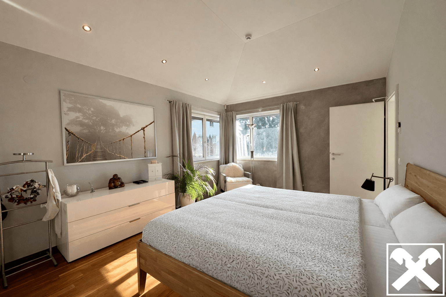 Gemütliches Schlafzimmer mit Holzbett, Dachschräge und großen Fenstern für viel Licht.