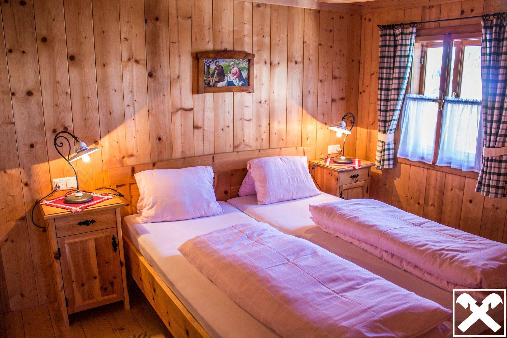 Schlafzimmer mit zwei Einzelbetten, Holzvertäfelung und einem Fenster für natürliches Licht.
