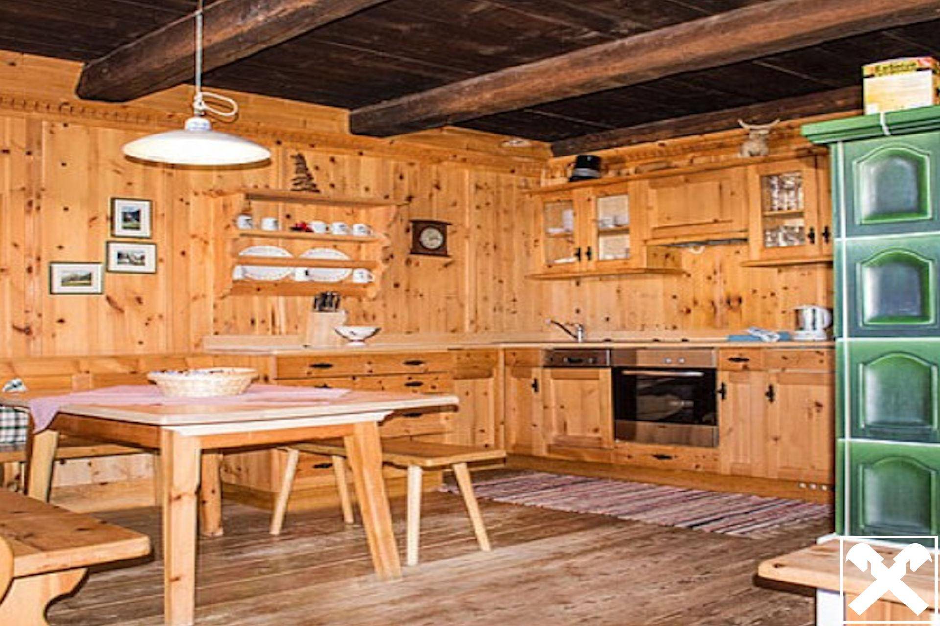 Gemütliche Wohnküche im alpenländischen Stil mit Holzeinrichtung, Essbereich und Kachelofen.