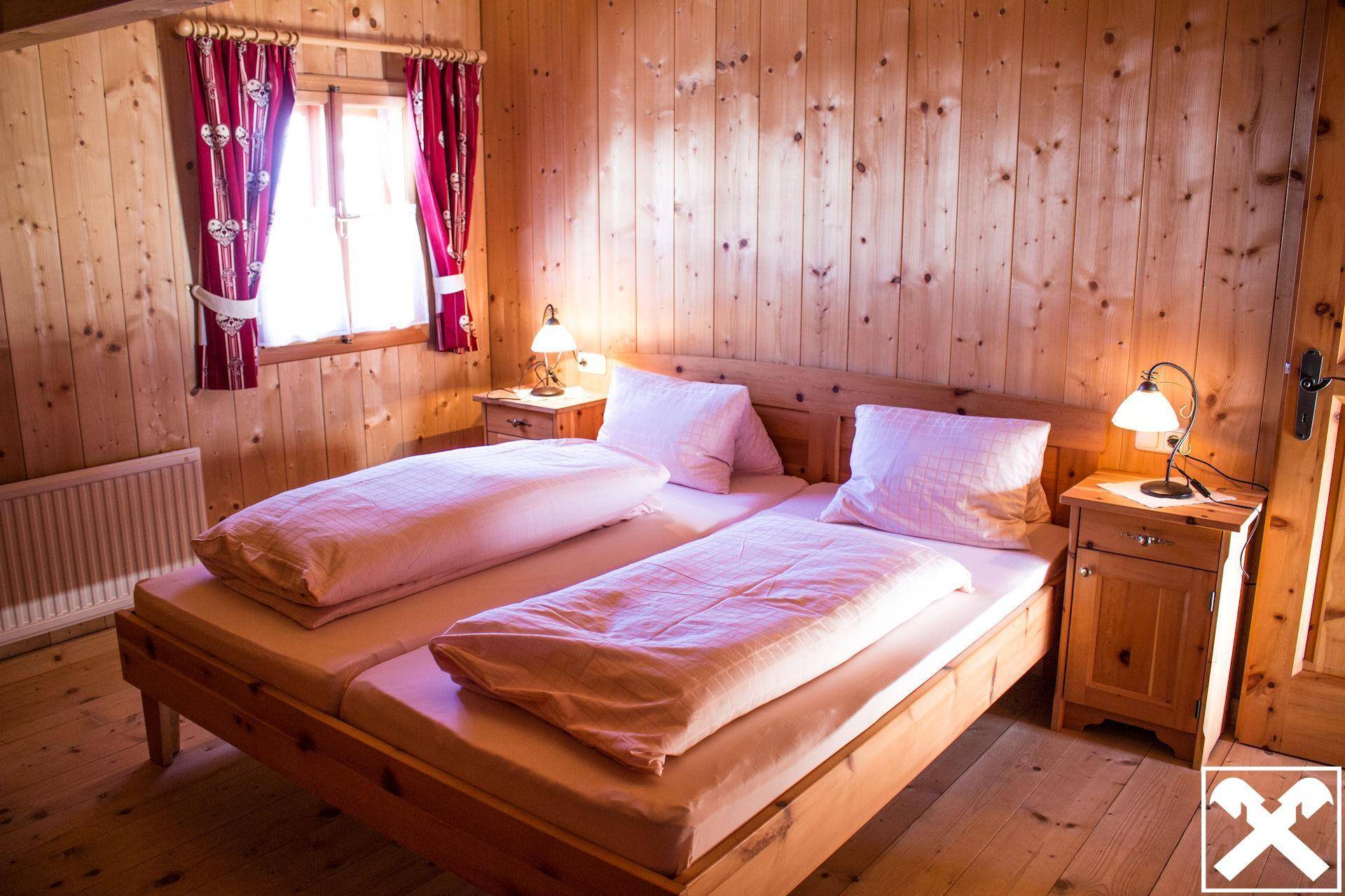 Helles Schlafzimmer mit Holztäfelung, zwei Einzelbetten und Blick ins Grüne.