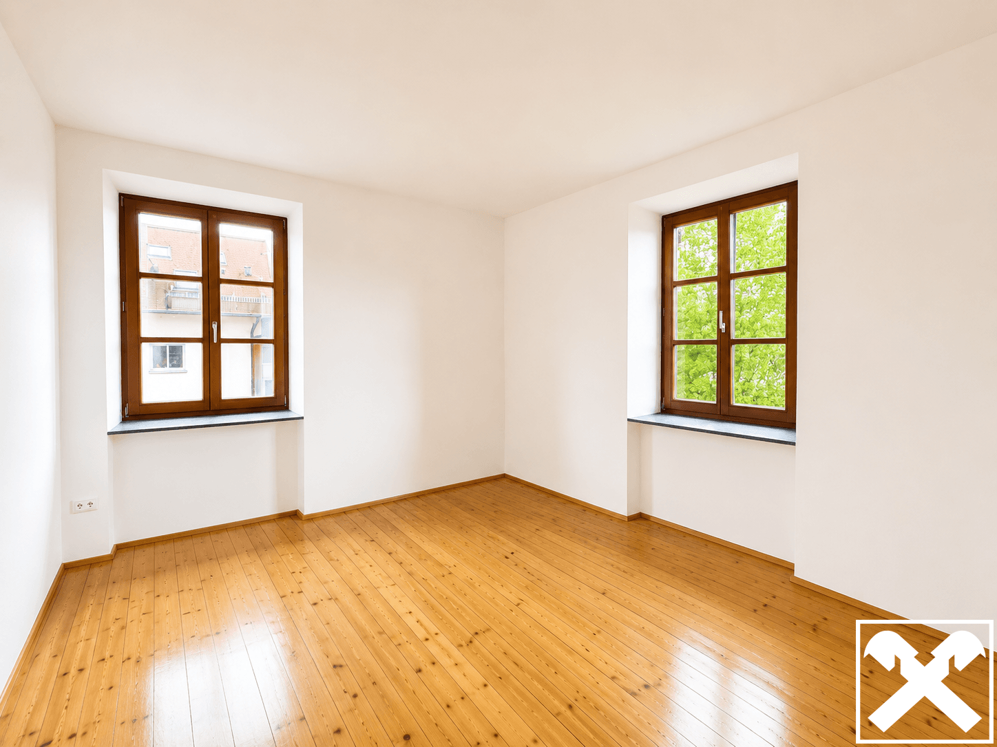 Heller, leerer Raum mit Holzdielenboden und zwei Fenstern, bereit zur individuellen Gestaltung.