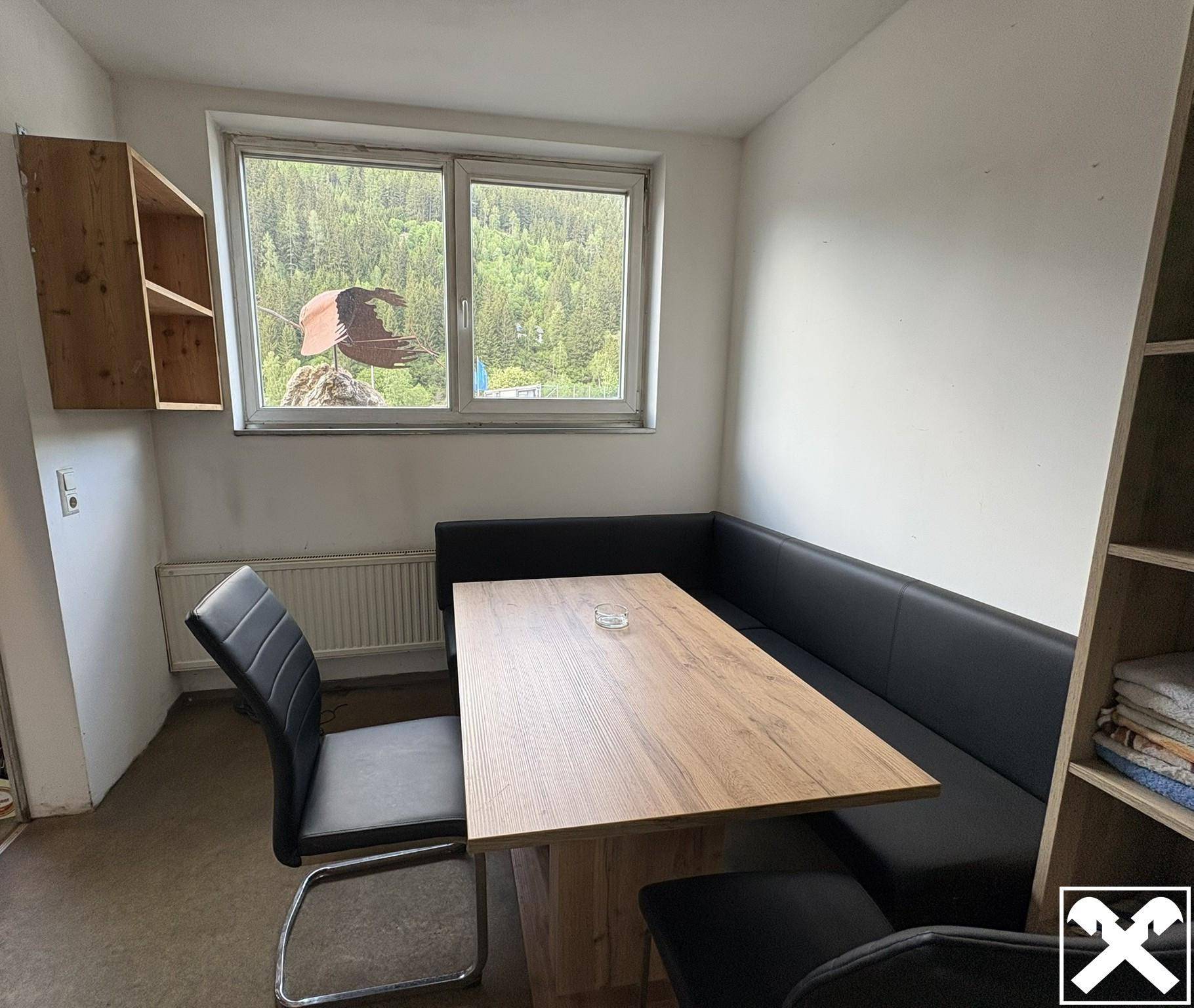 Gemütlicher Essbereich mit Holztisch und Sitzbank, bietet einen schönen Ausblick auf die umliegende grüne Berglandschaft.