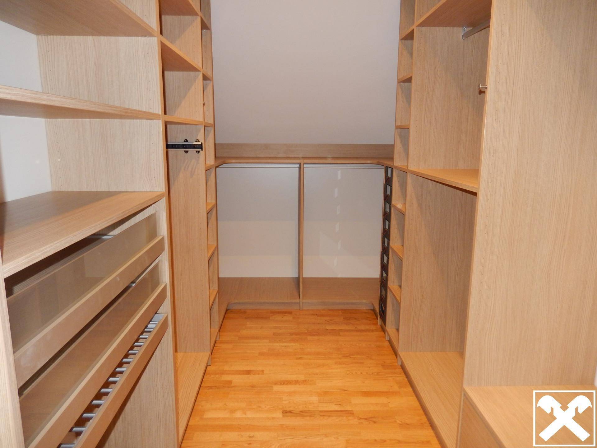 Geräumiger begehbarer Kleiderschrank mit maßgefertigten Holzregalen und viel Stauraum.