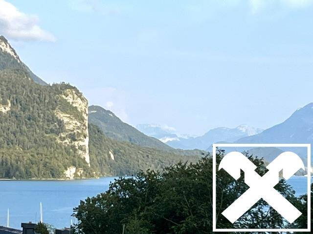 Panoramablick auf den ruhigen See, umgeben von majestätischen Bergen und üppiger grüner Natur.