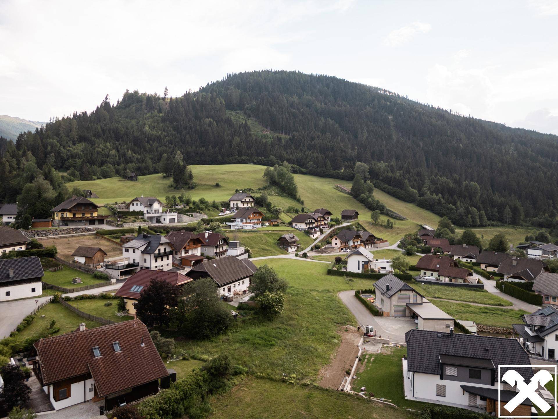 Weitläufige Ansicht der ländlichen Siedlung eingebettet in eine malerische Berglandschaft mit Wäldern.